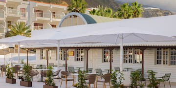 a white building with tables and chairs and umbrellas