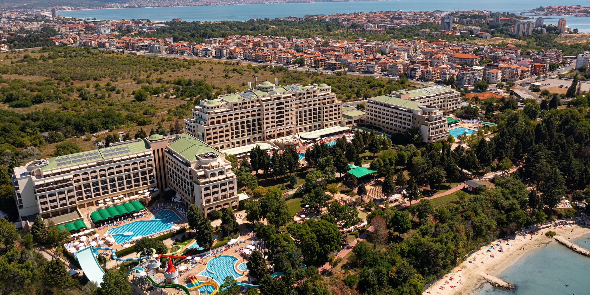 a large building with a pool and trees next to a beach