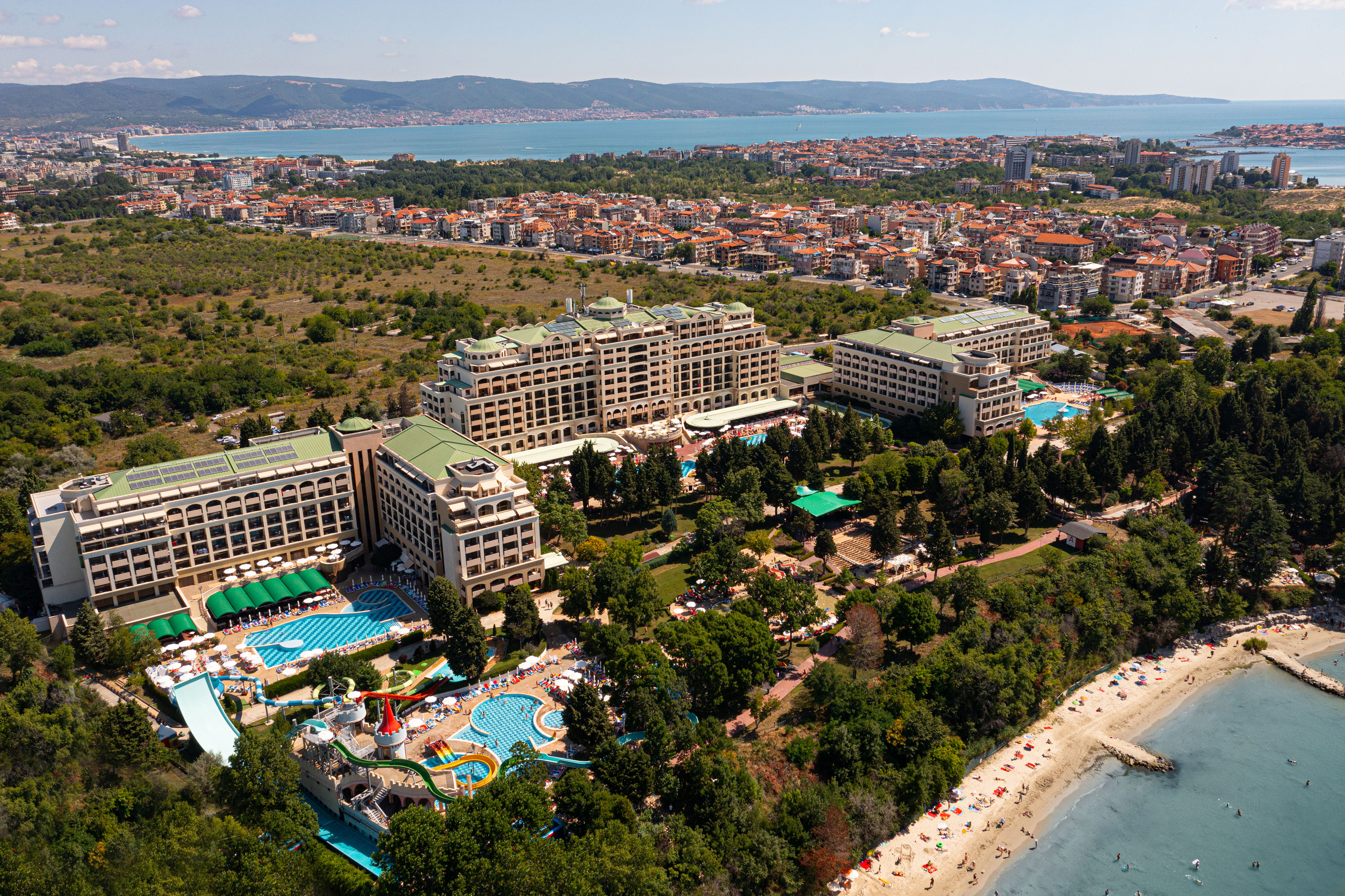 a large building with a pool and trees next to a beach