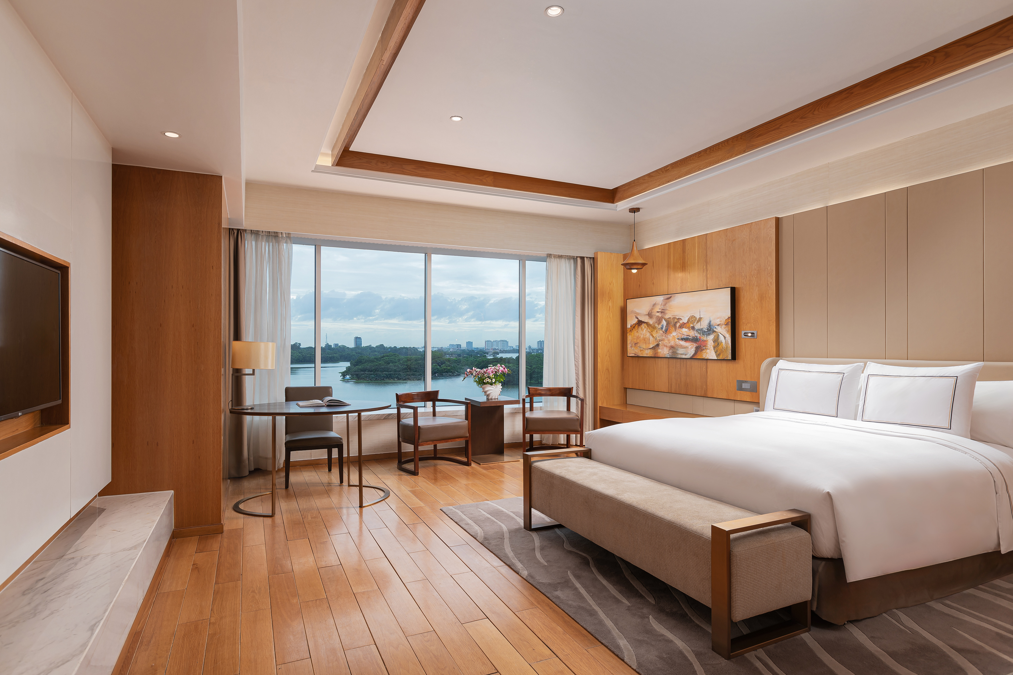 Modern luxury hotel room with scenic river view and king bed.