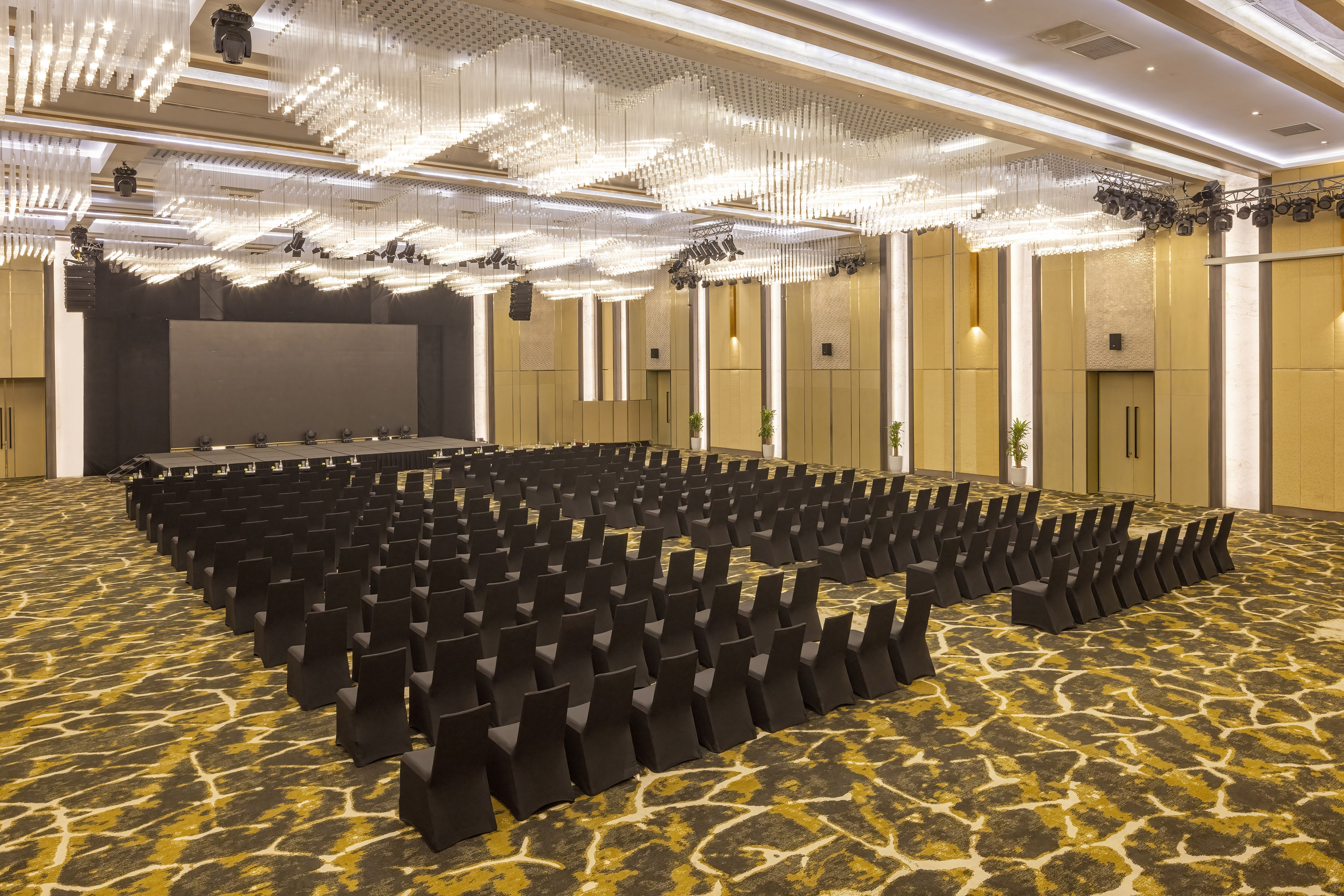 Empty conference ballroom with black chairs, stage, large screen, and elaborate ceiling lights. - Grand Ballroom - Meliá Vinpearl Thanh Hoa, Thanh Hoa