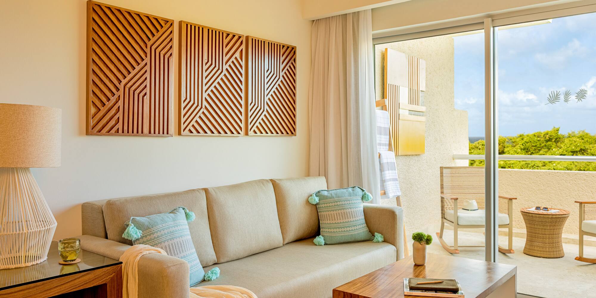 Modern resort living room with sofa, wood art, and balcony view.
