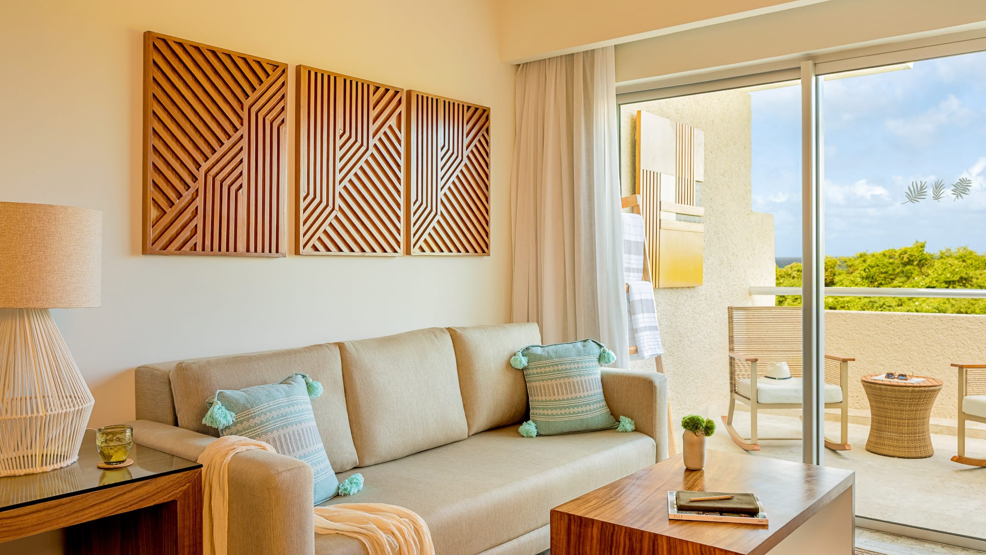 Modern resort living room with sofa, wood art, and balcony view.