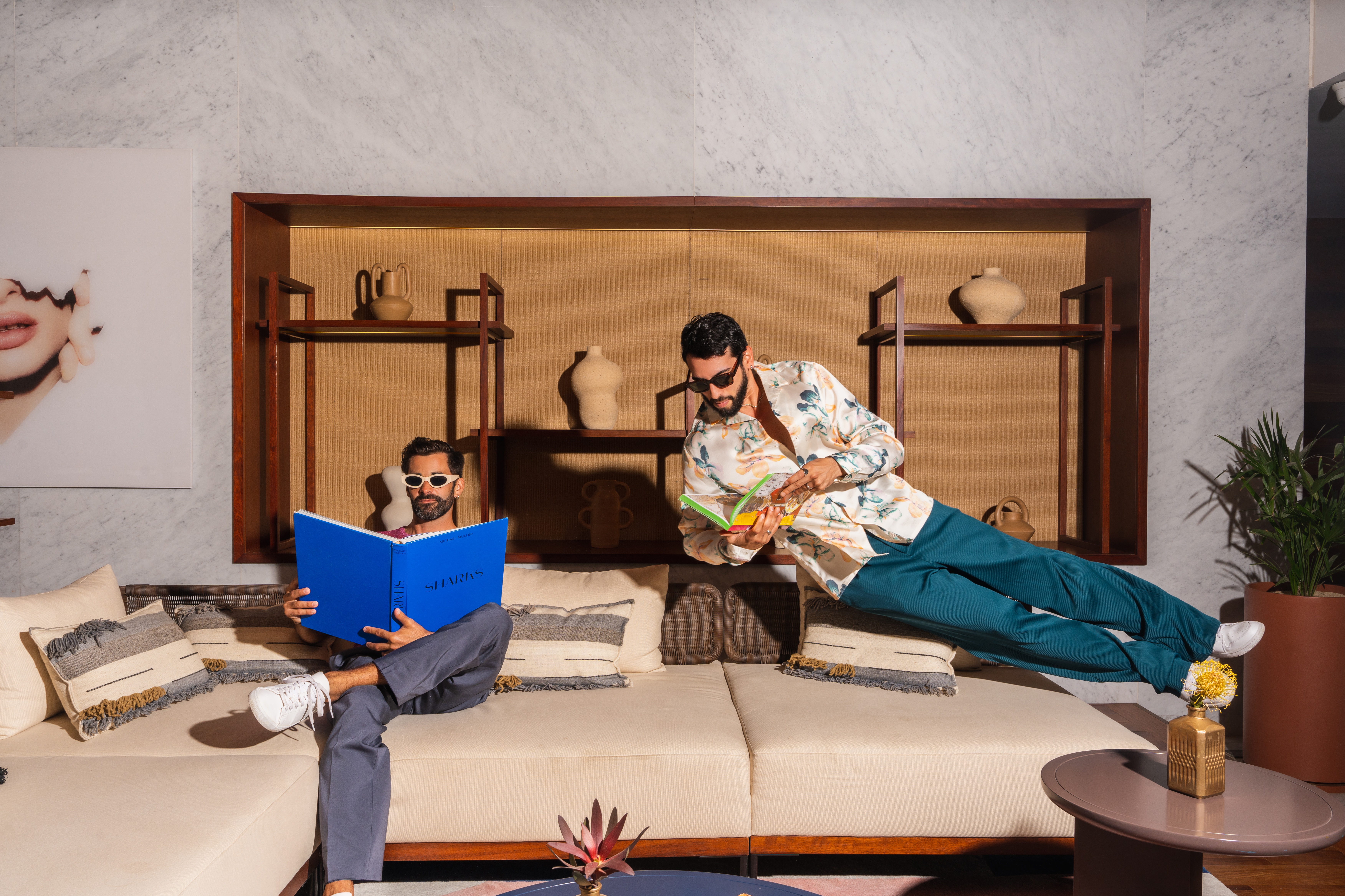 Stylish men reading, one levitating, in a chic modern living room.