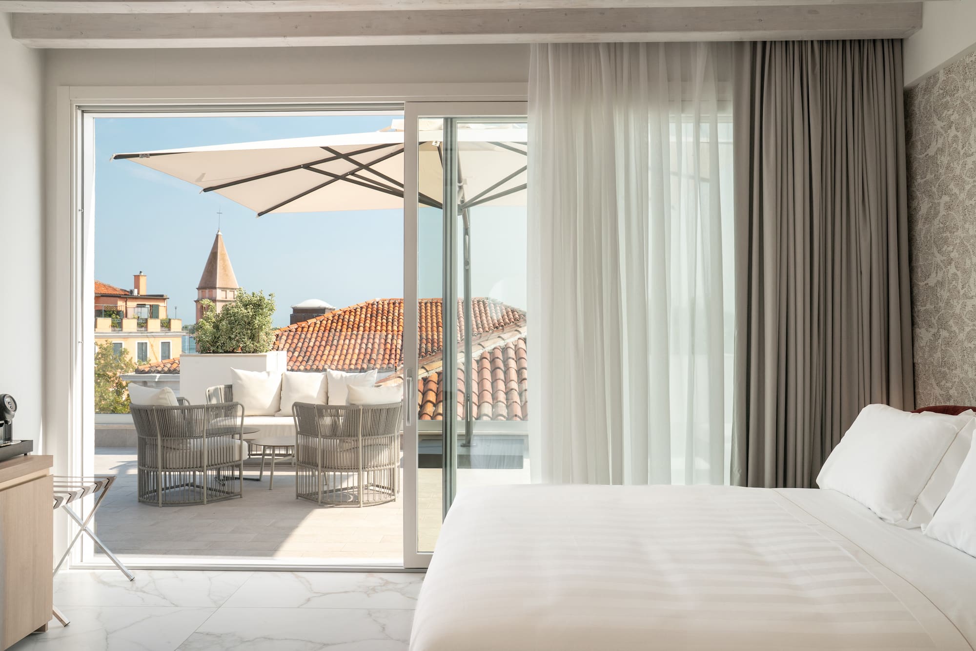 Bedroom with private terrace, outdoor seating, and historic city view.