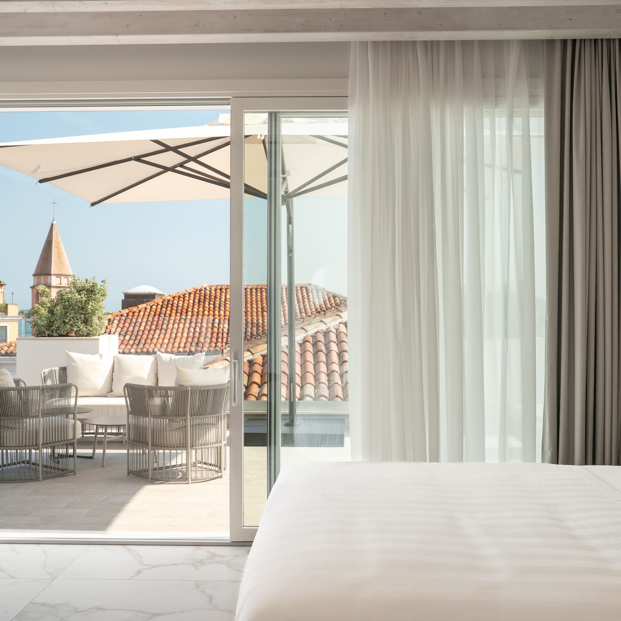Bedroom with private terrace, outdoor seating, and historic city view.