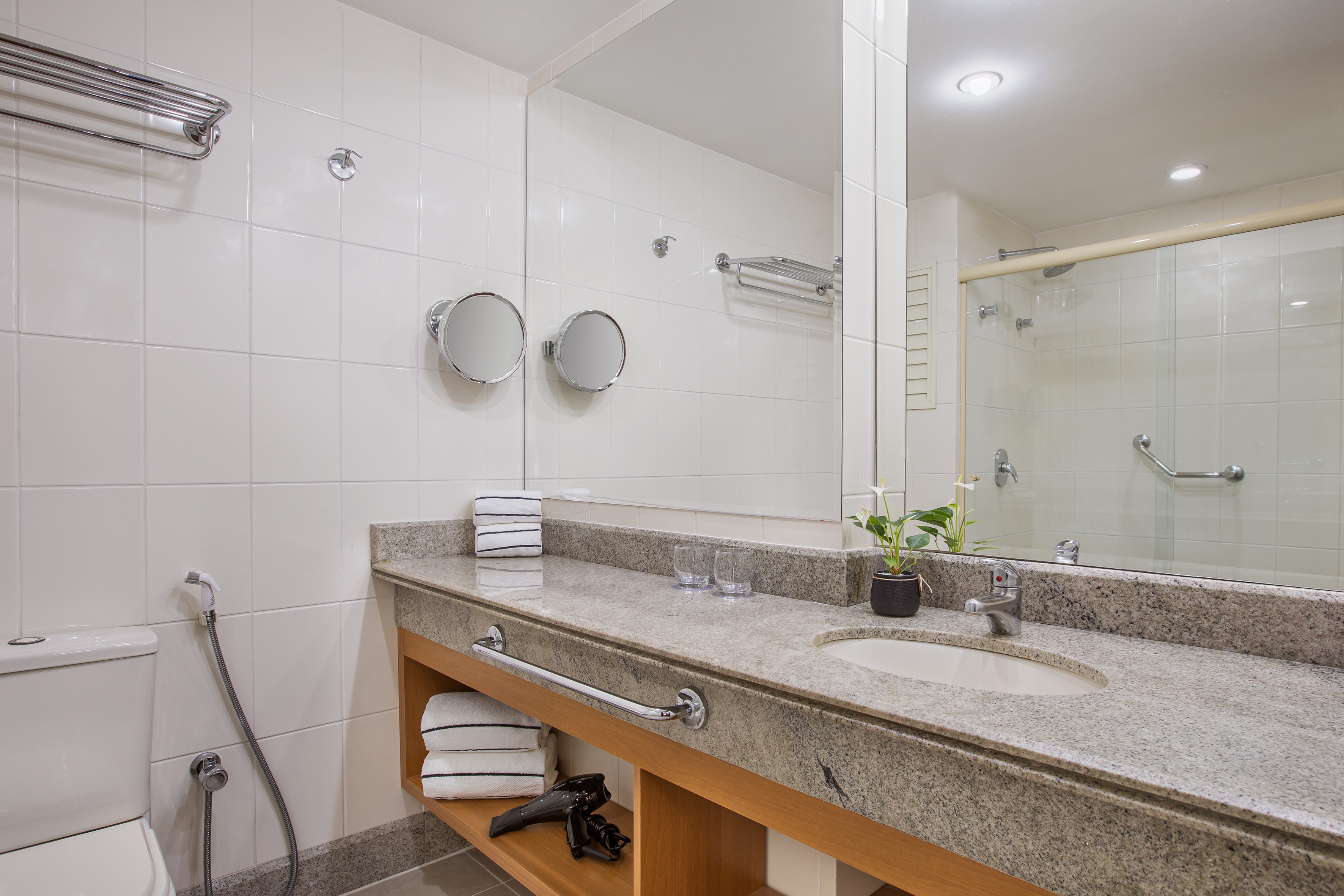 Clean modern hotel bathroom with granite vanity, sink, and shower.