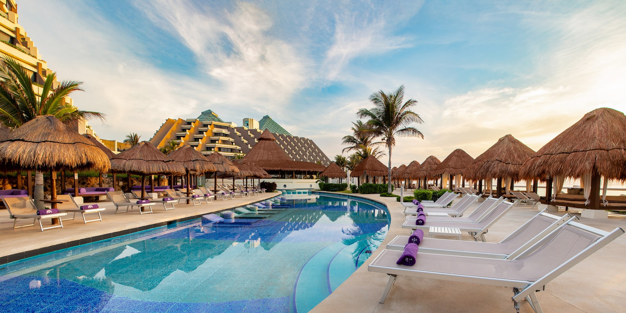 a pool with straw umbrellas and lounge chairs