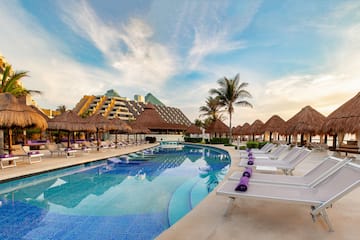 a pool with straw umbrellas and lounge chairs