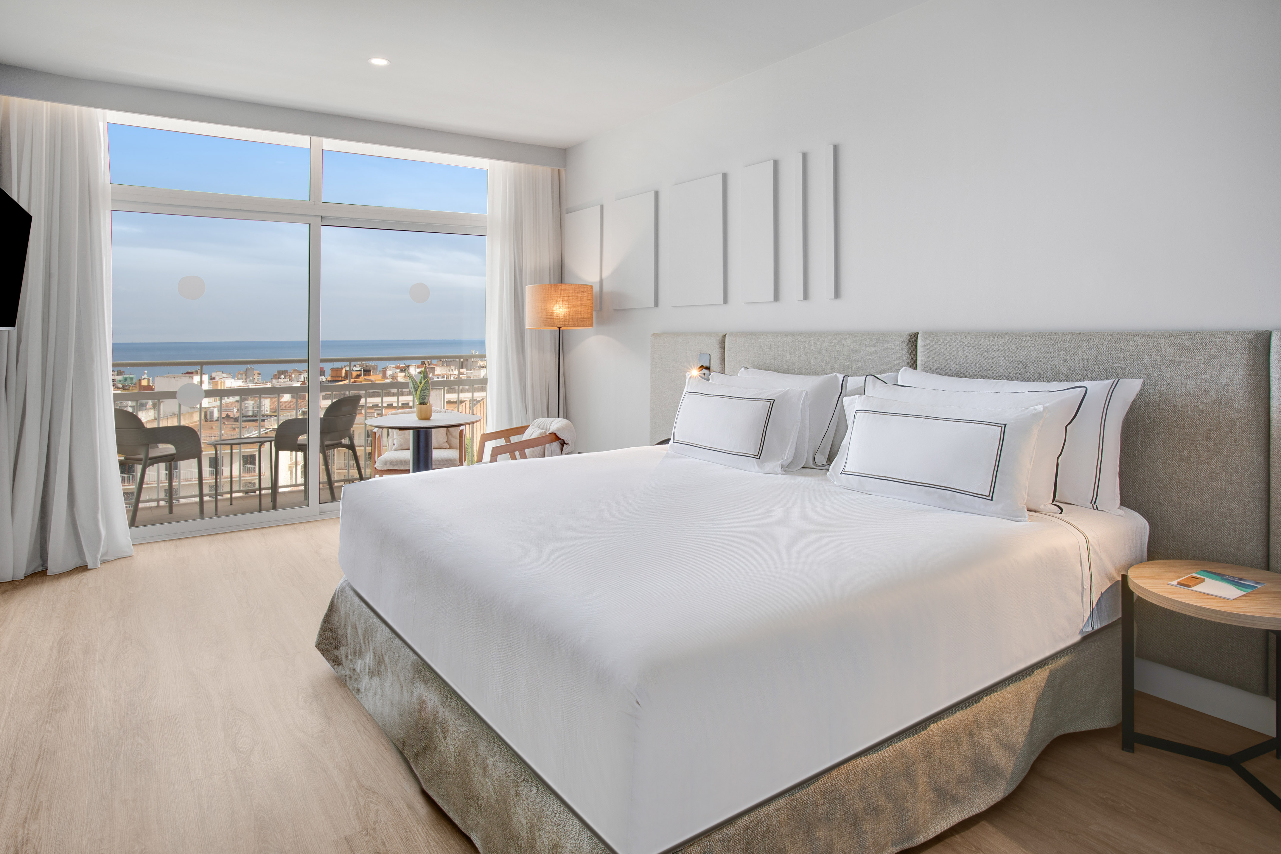 Oceanfront hotel room with balcony, city view, and king bed.