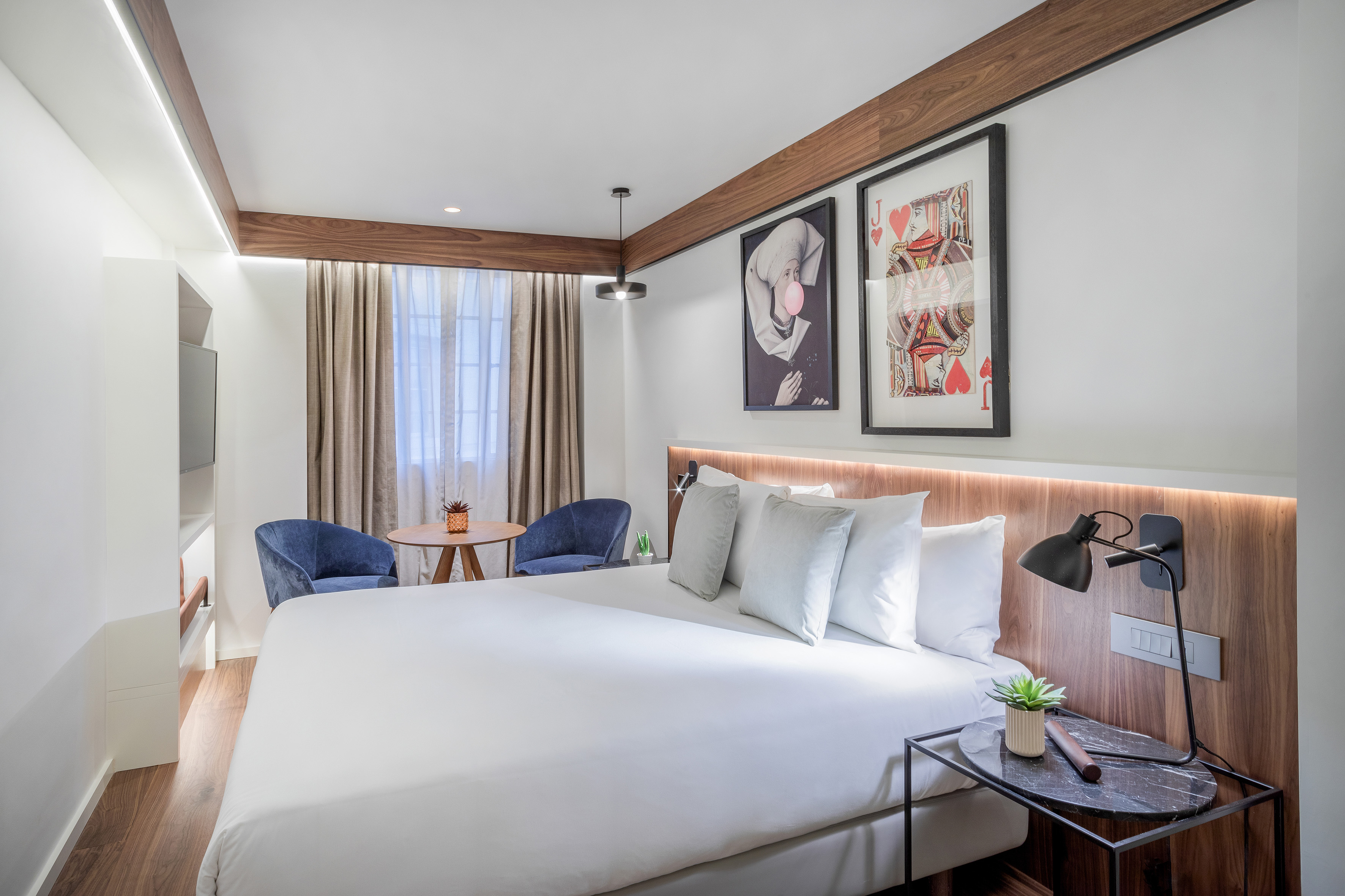 Modern hotel bedroom with king bed, wood paneling, and bold wall art.