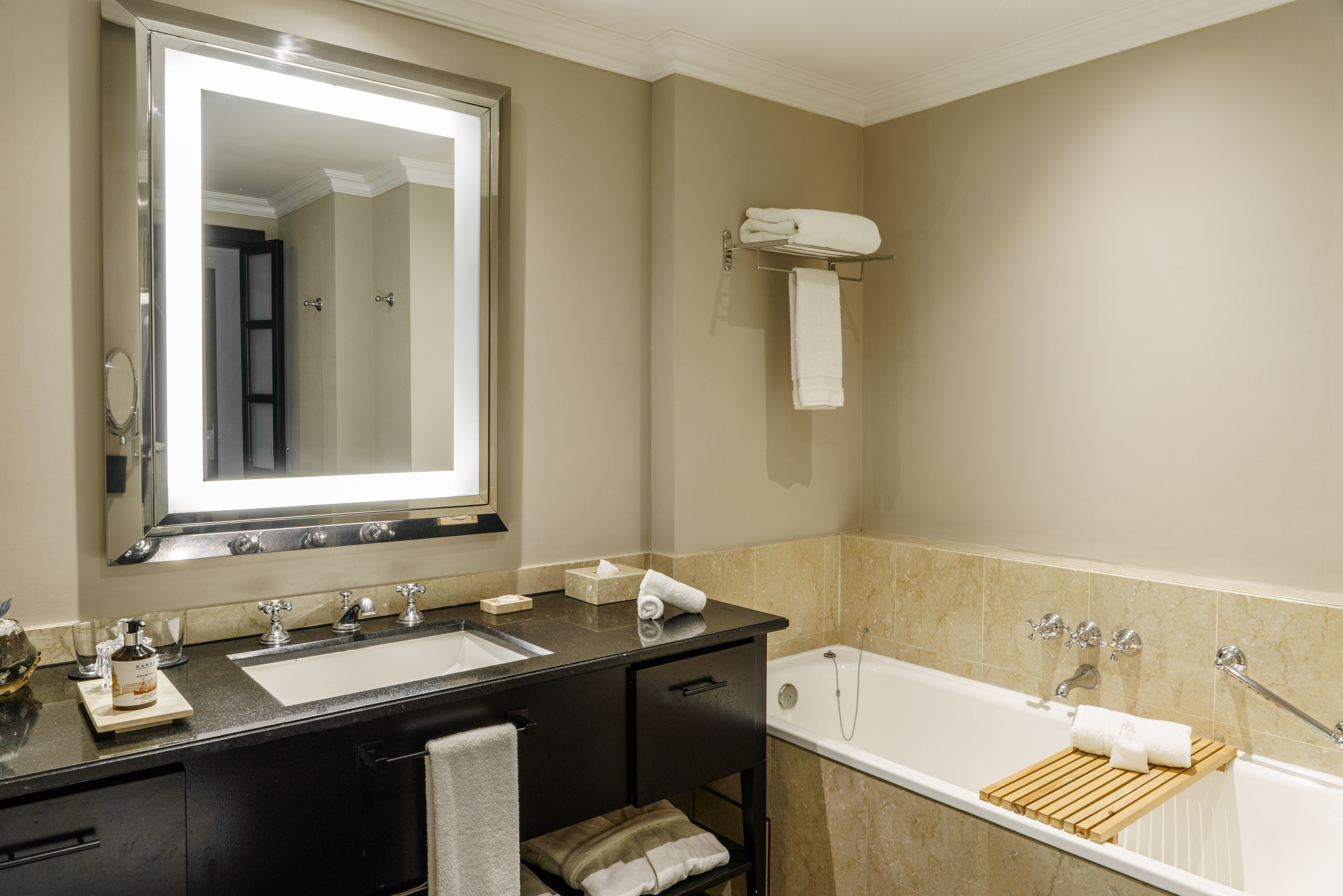 Luxurious hotel bathroom featuring vanity, lighted mirror, and bathtub.