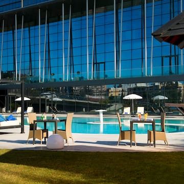 a pool with chairs and tables in front of a building
