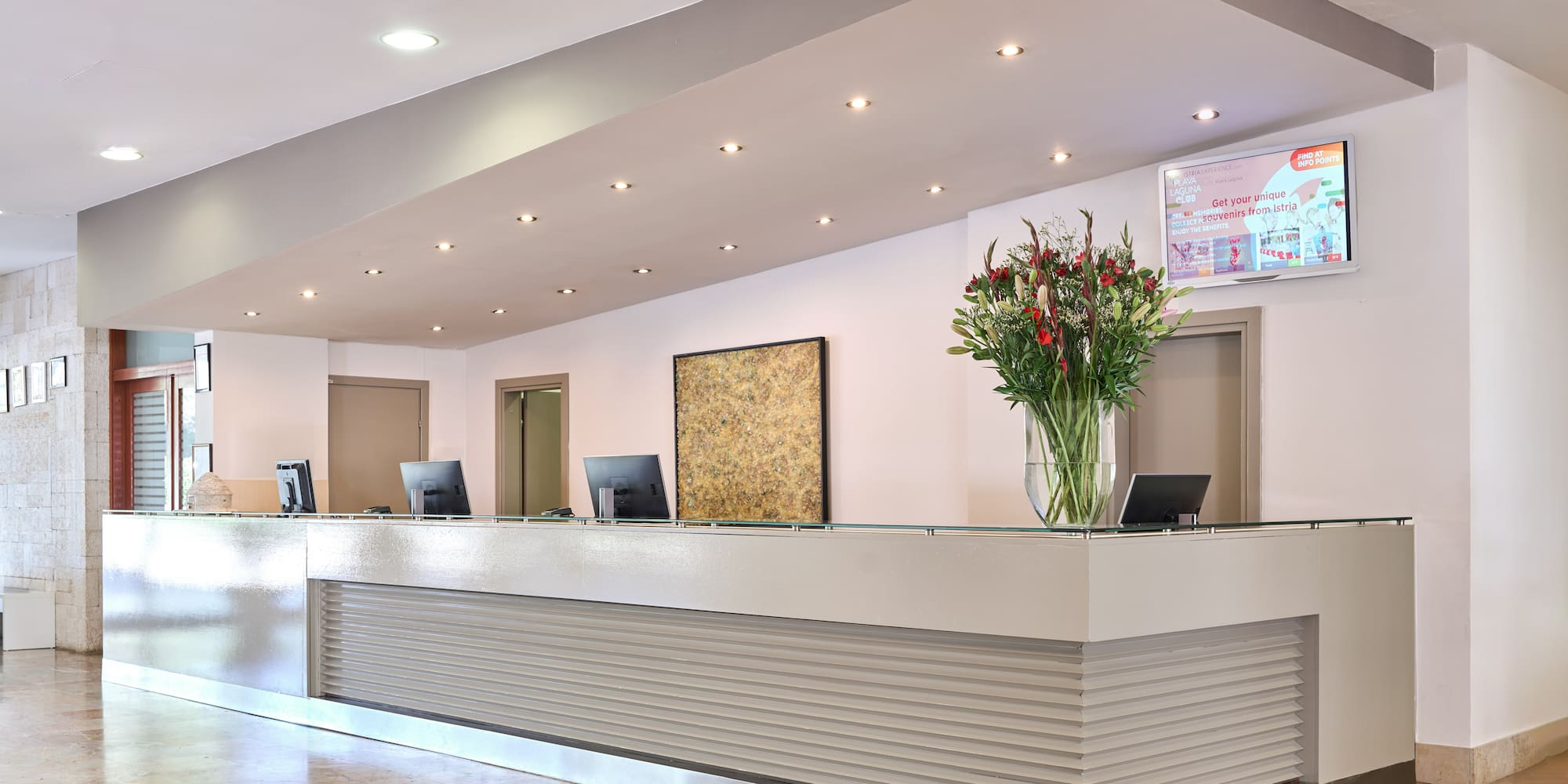 a reception desk with computers and flowers in a vase