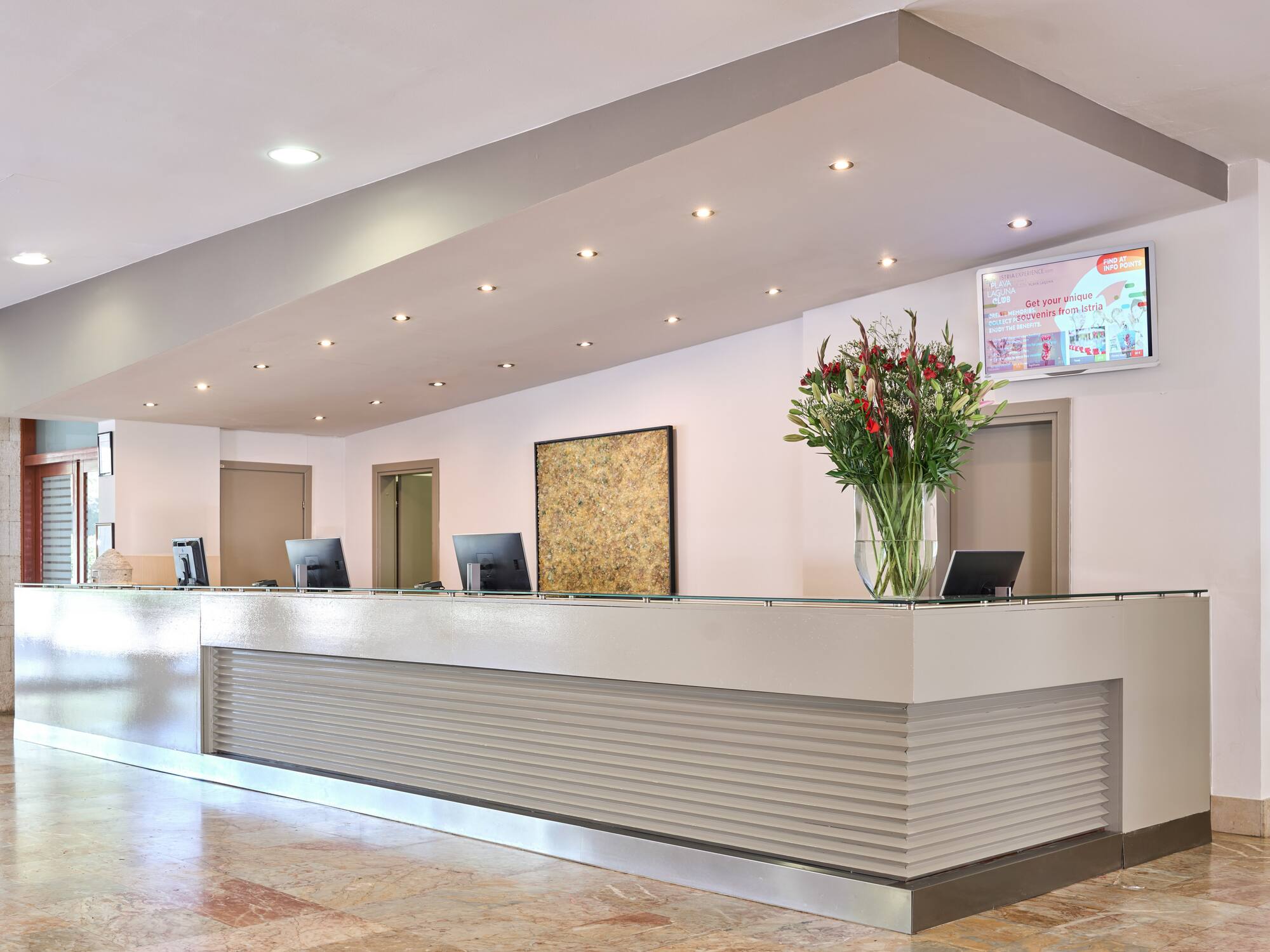 a reception desk with computers and flowers in a vase