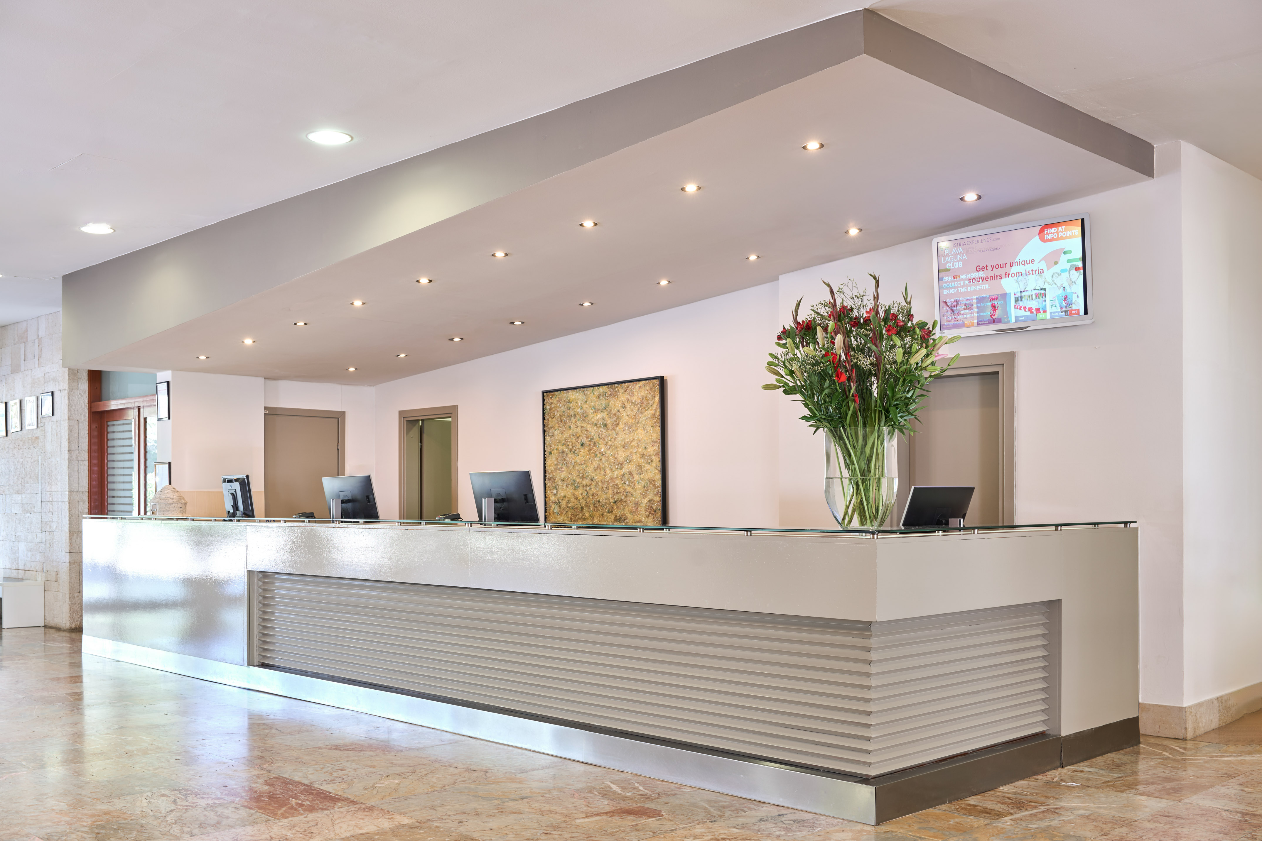 a reception desk with computers and flowers in a vase