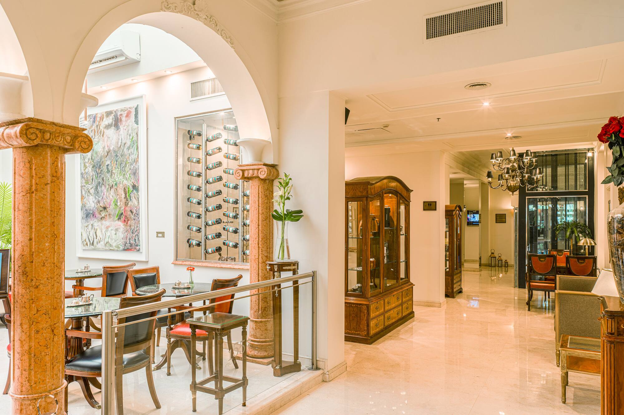Luxury hotel lobby with arched entry, cafe seating, and wine display.