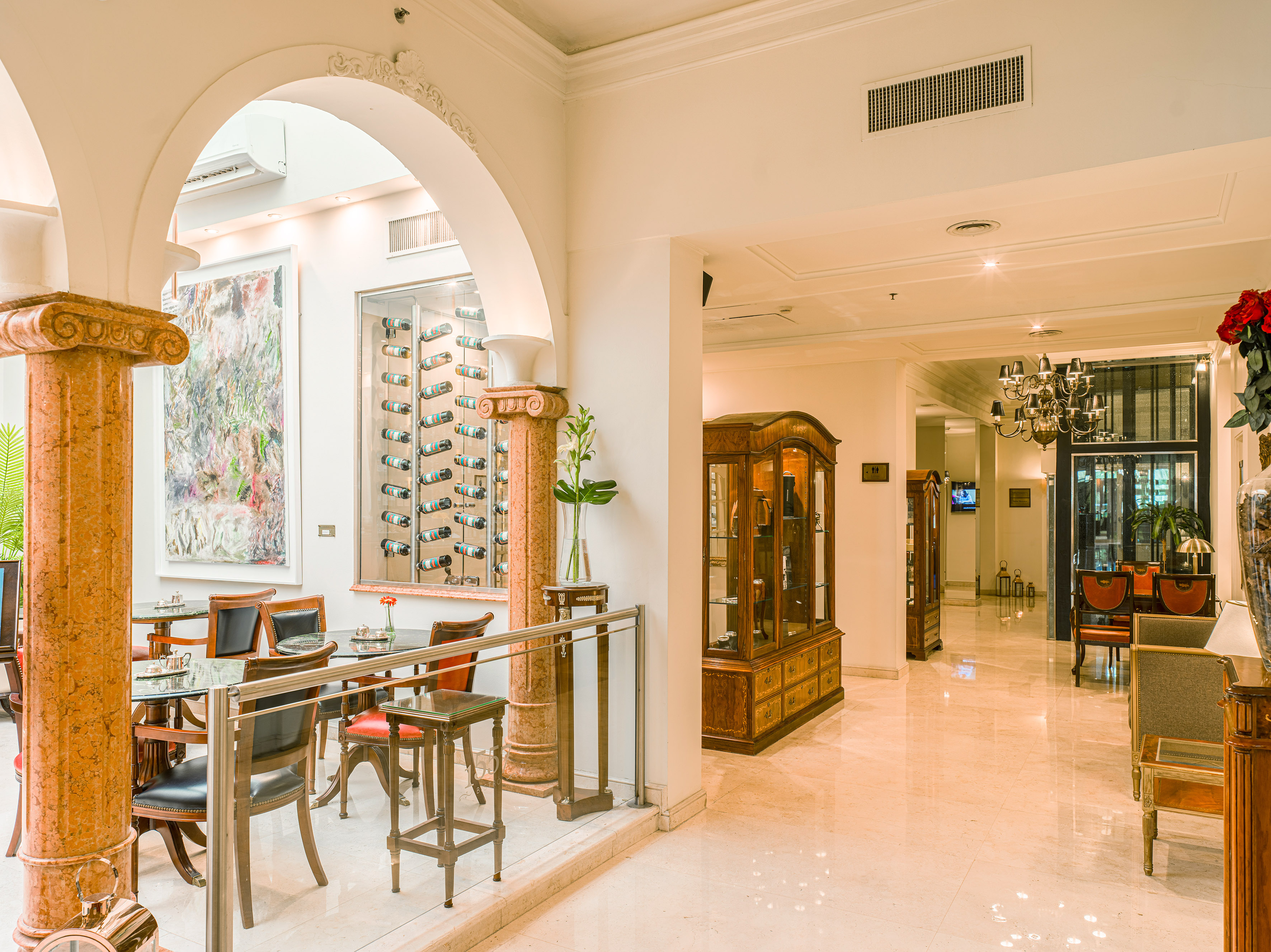 Luxury hotel lobby with arched entry, cafe seating, and wine display.