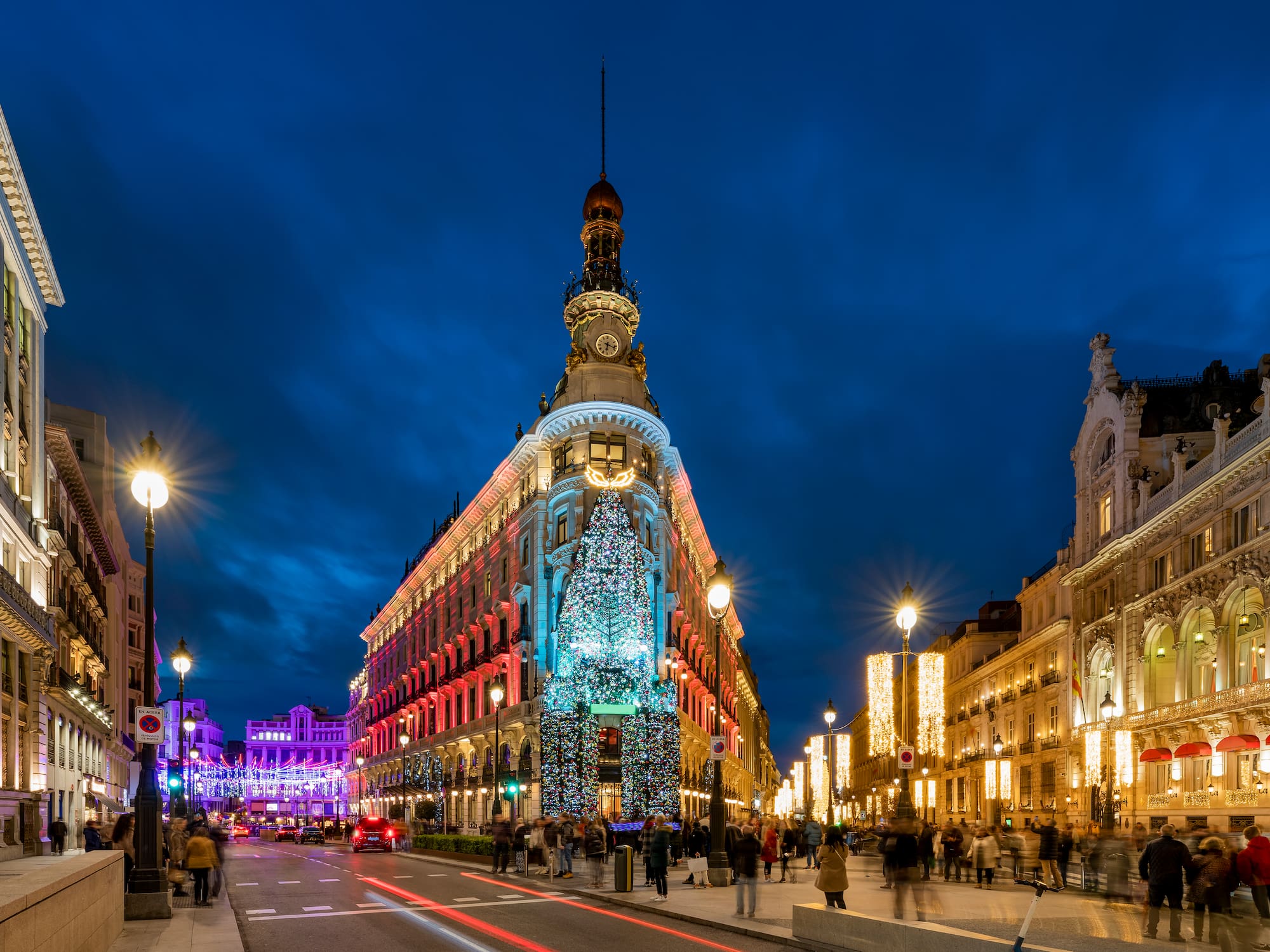 A city street filled with lights and bustling with pedestrians.