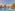 Tropical resort pool, palm trees, sunbeds, and hotel buildings under a clear sky.