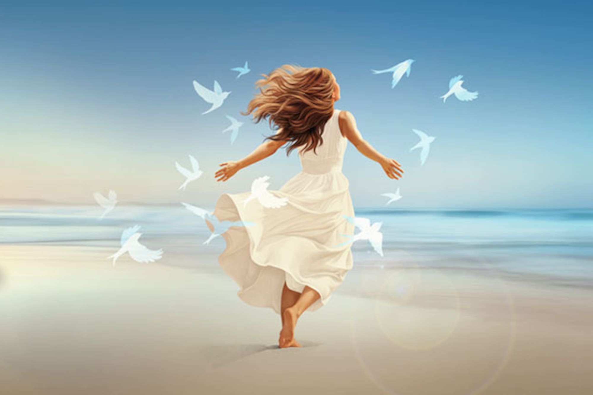 Woman in white dress, arms open, birds flying on sunny beach by ocean.