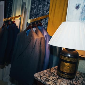 a room with suits on swingers and a lamp