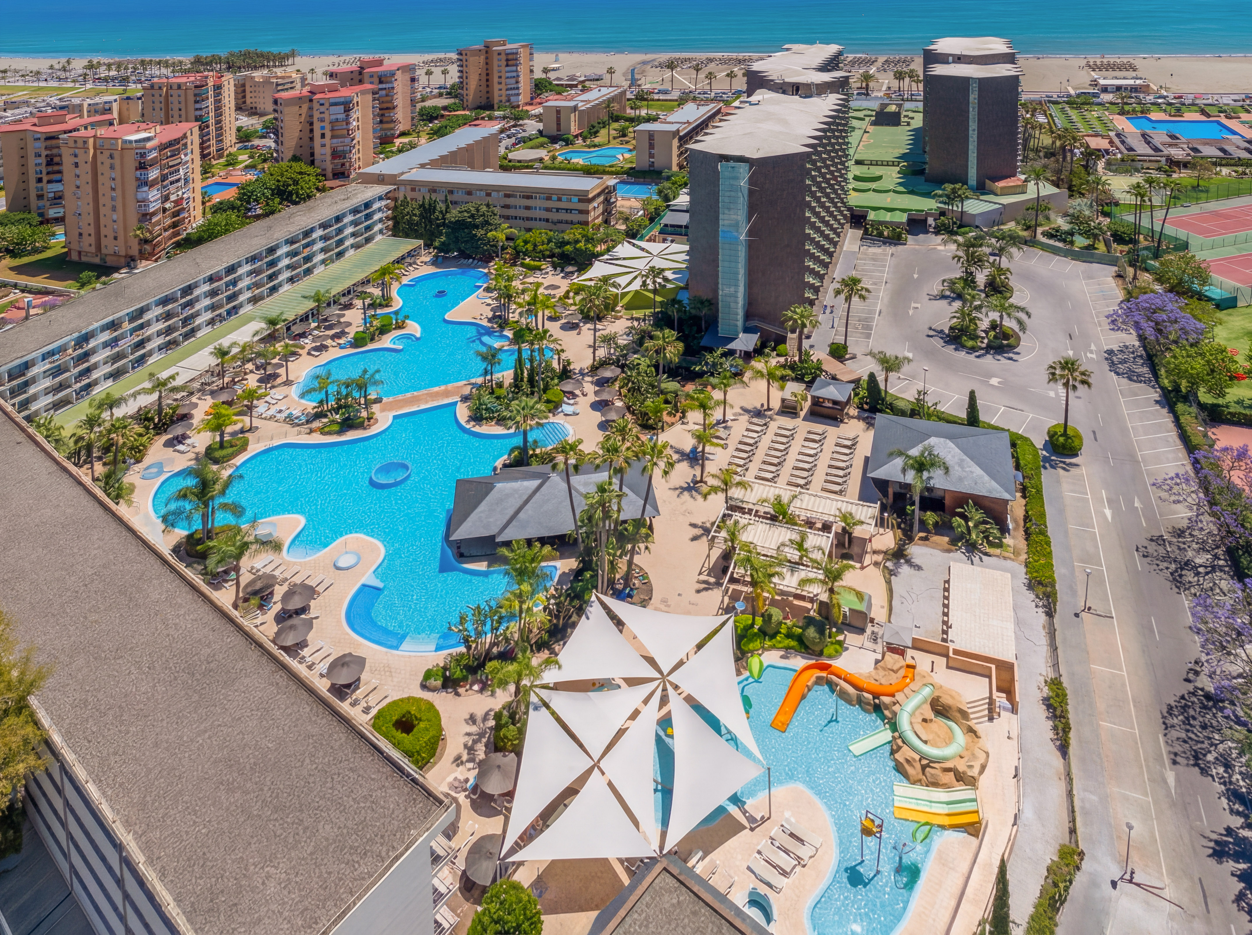 Beach resort aerial view: multiple pools, waterslides, hotels, ocean.