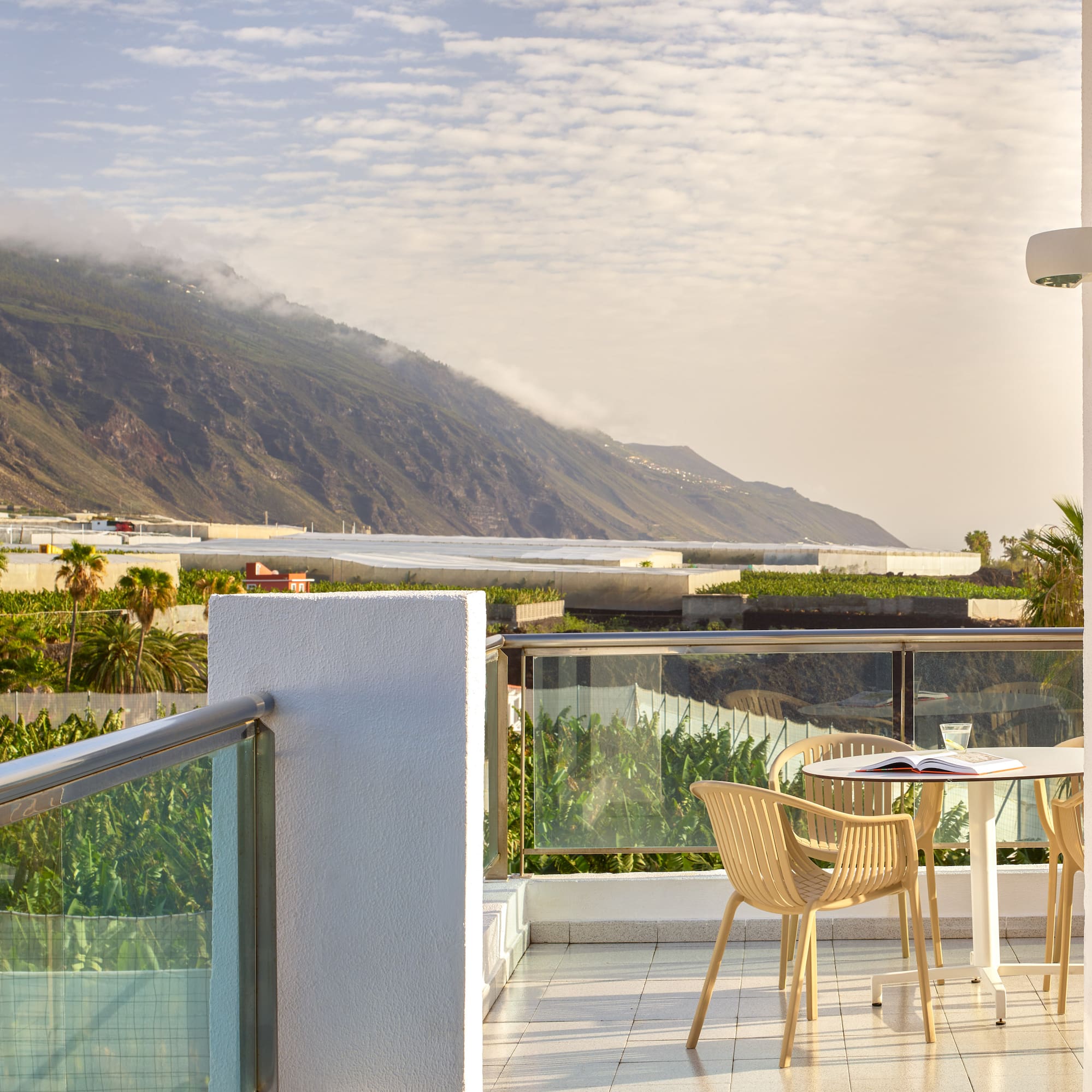 a table and chairs on a balcony overlooking a mountain