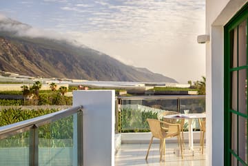 a table and chairs on a balcony overlooking a mountain