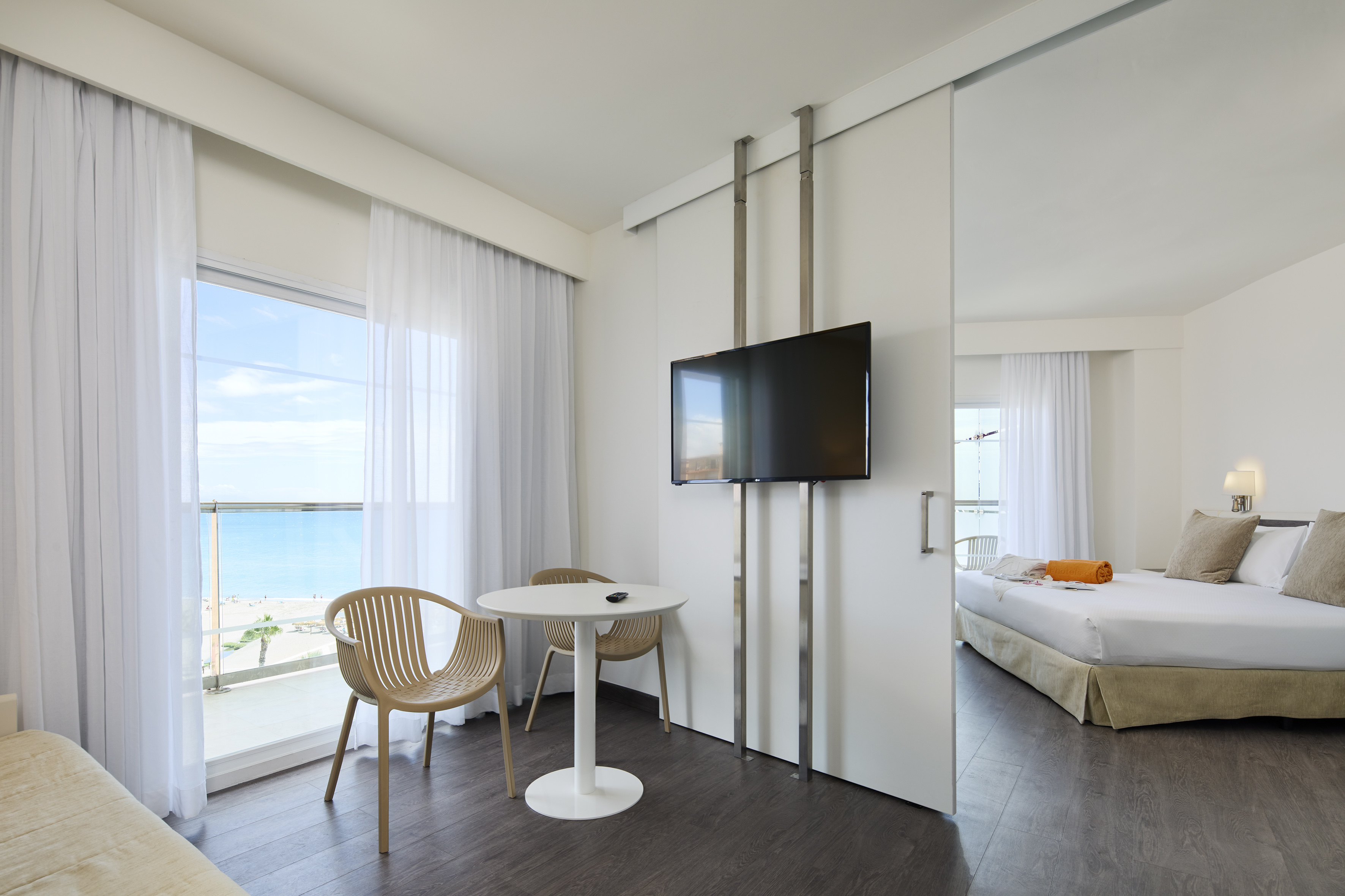 Modern hotel suite with ocean view, balcony, and separate bedroom.