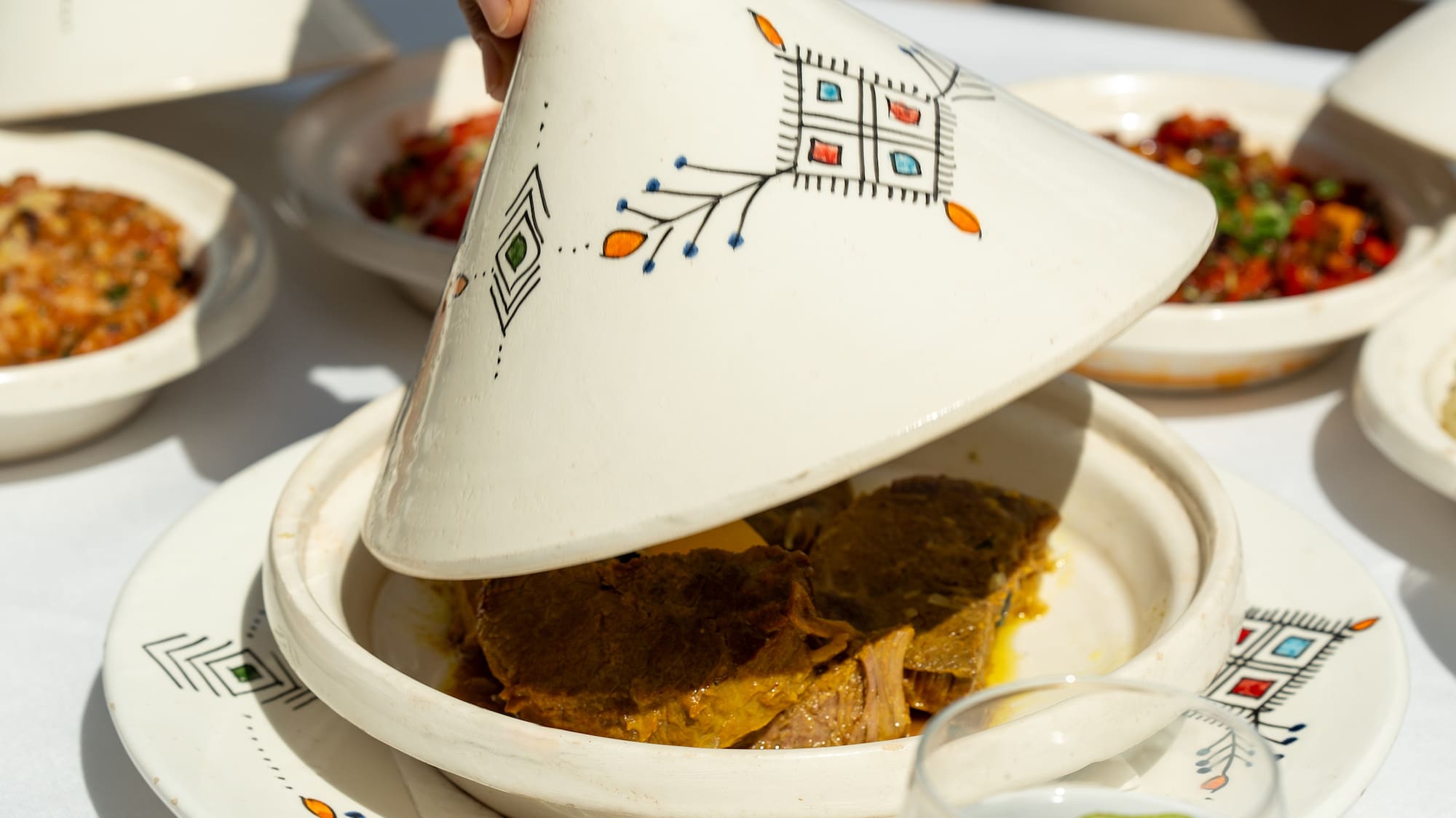a person holding a tagine over a plate of food