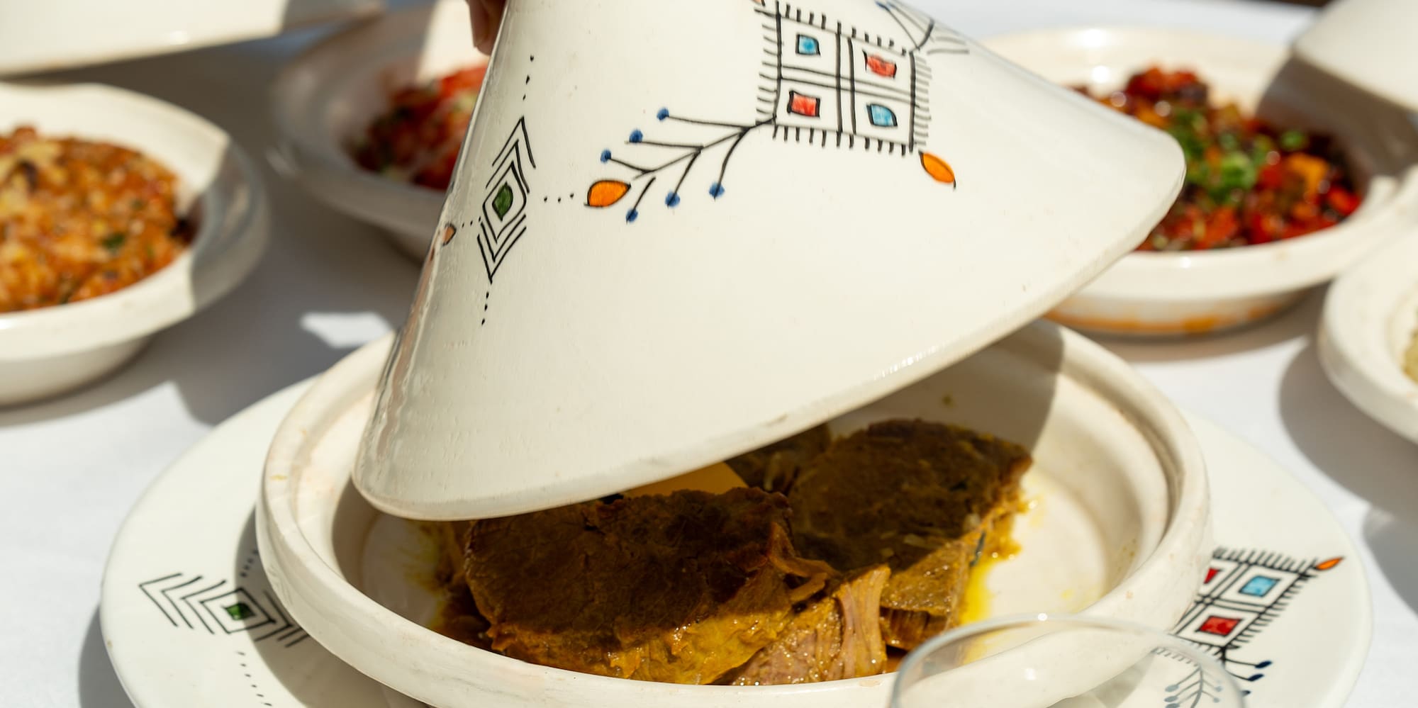 a person holding a tagine over a plate of food