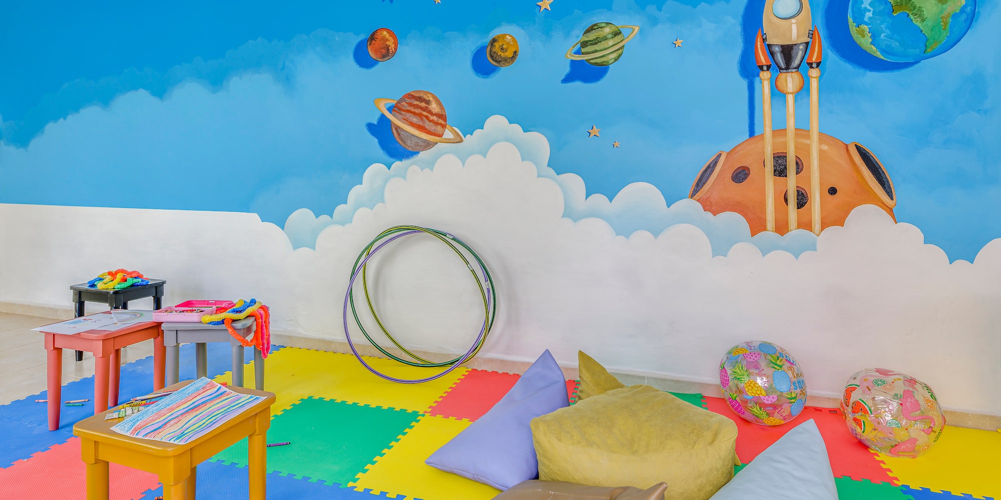 a room with a mural of planets and a rocket