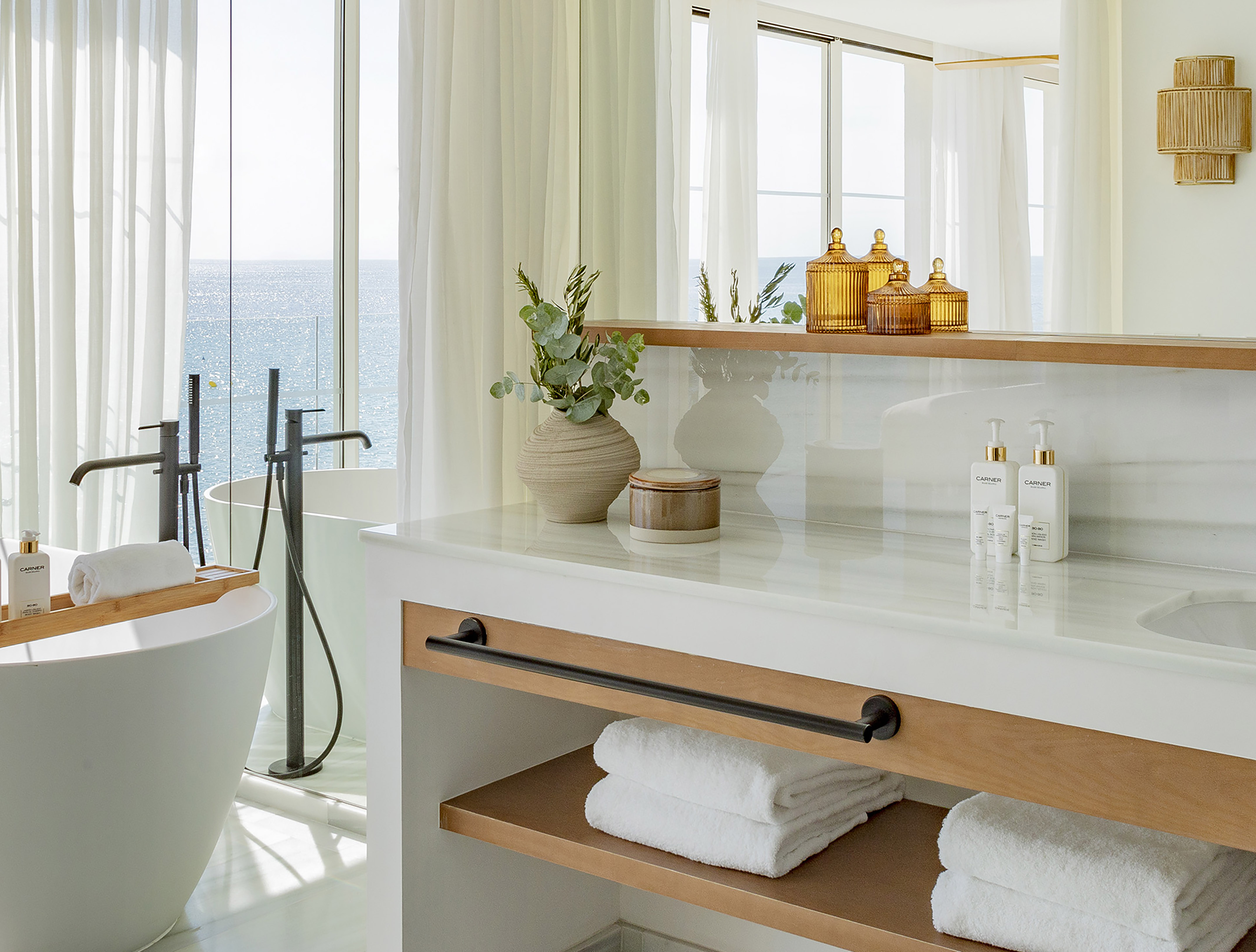 Spa-like bathroom with ocean view, freestanding tub, and white marble vanity.