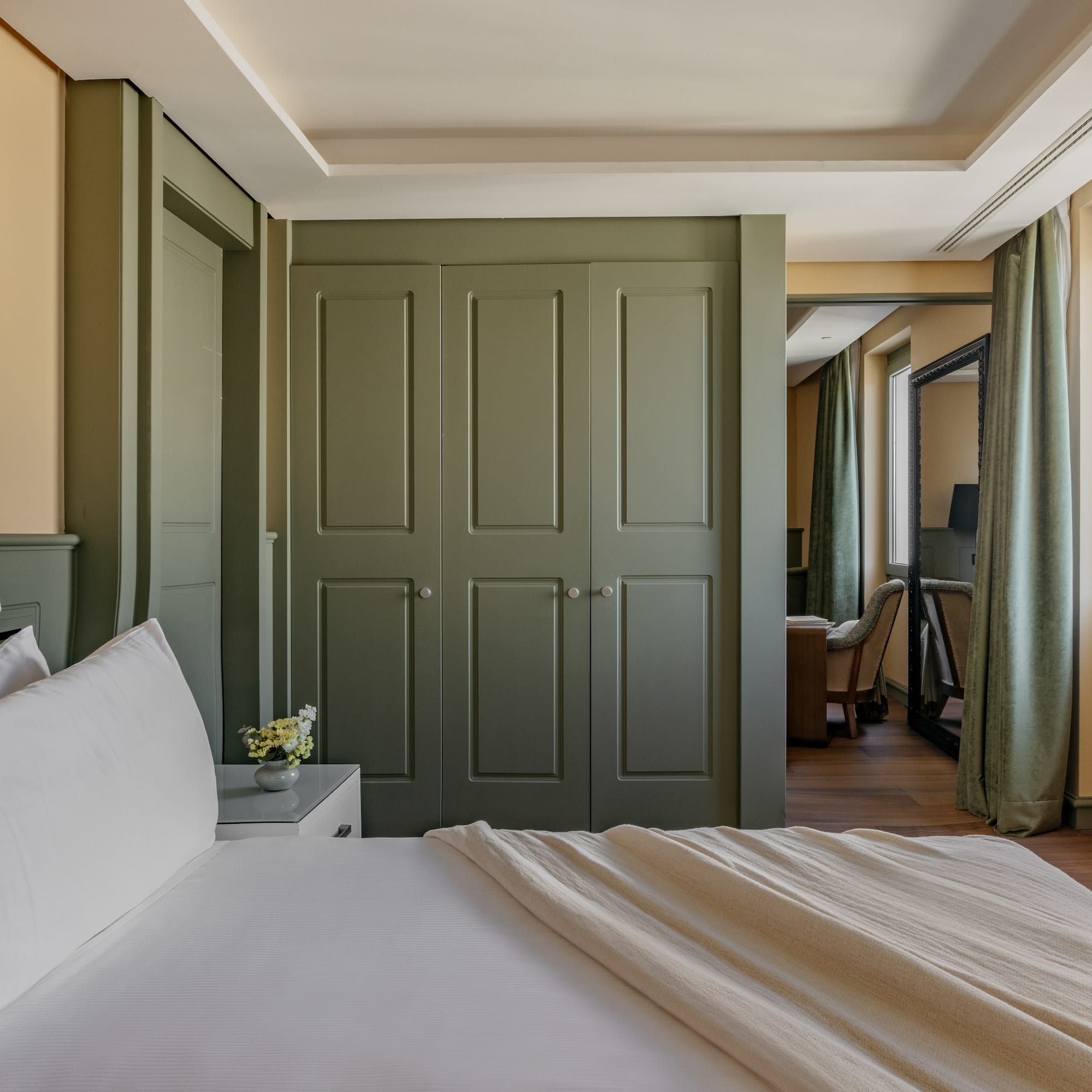 Dormitorio de lujo con cama, armario verde, pared dorada y ventana.