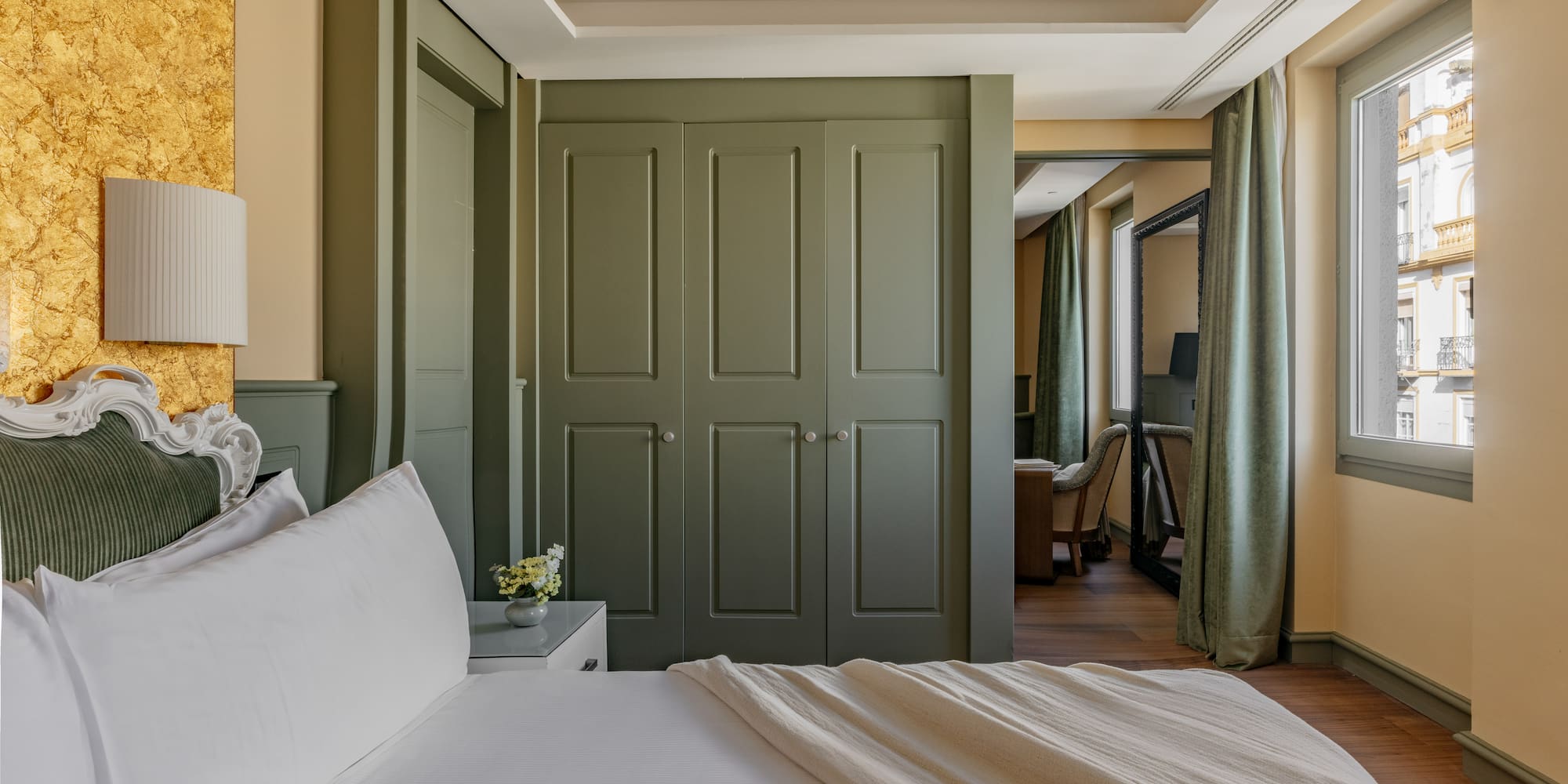 Dormitorio de lujo con cama, armario verde, pared dorada y ventana.