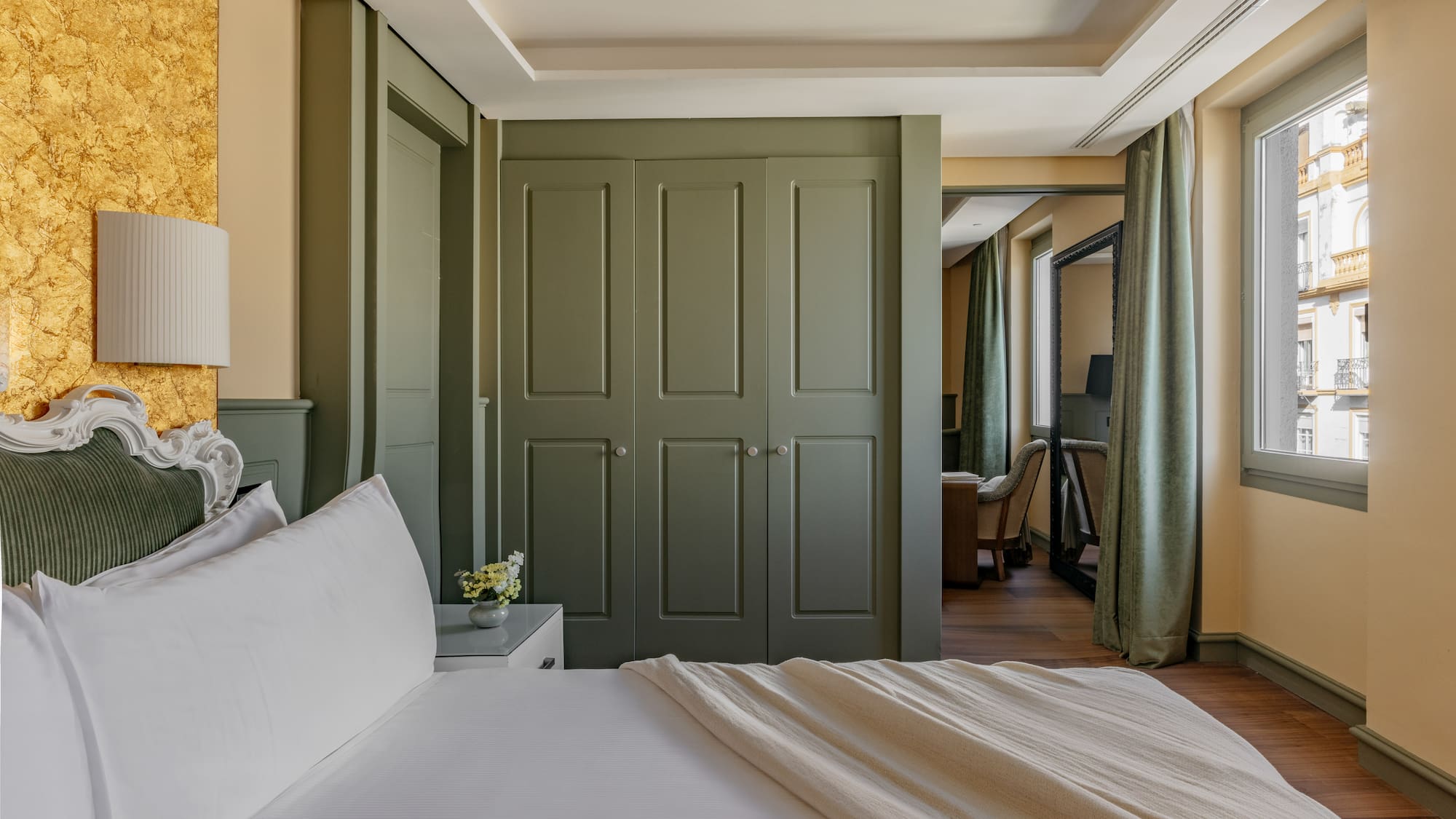 Dormitorio de lujo con cama, armario verde, pared dorada y ventana.
