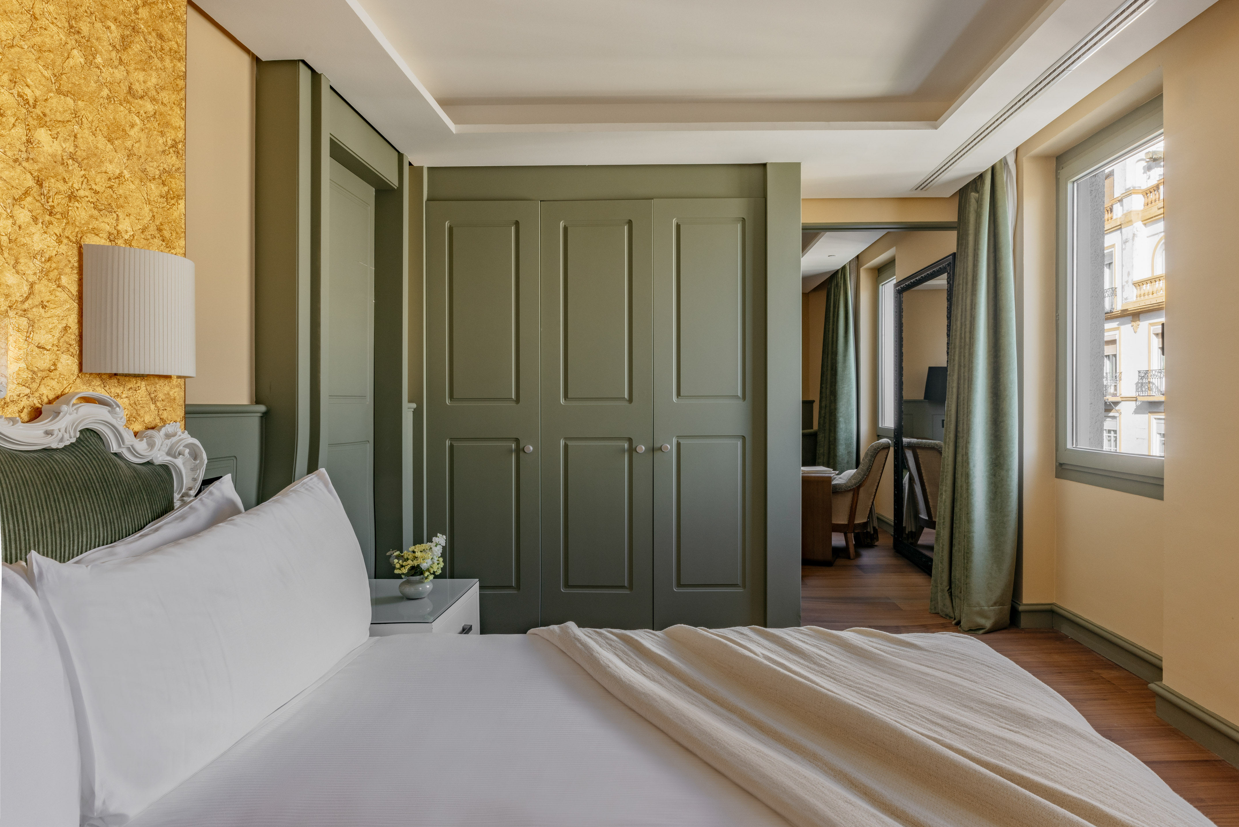 Dormitorio de lujo con cama, armario verde, pared dorada y ventana.