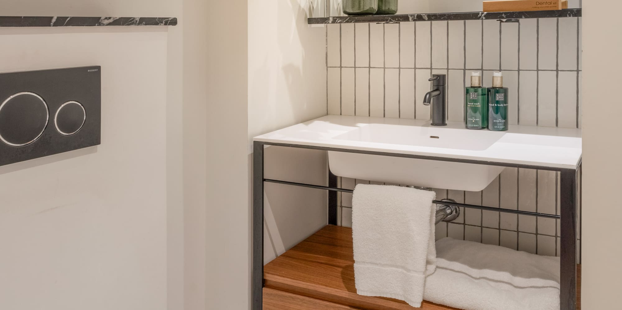 Modern bathroom with white toilet, sink, wooden vanity, mirror, and plant.
