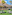 Resort thatched bar, outdoor seating on grass, palm trees, and hotel.