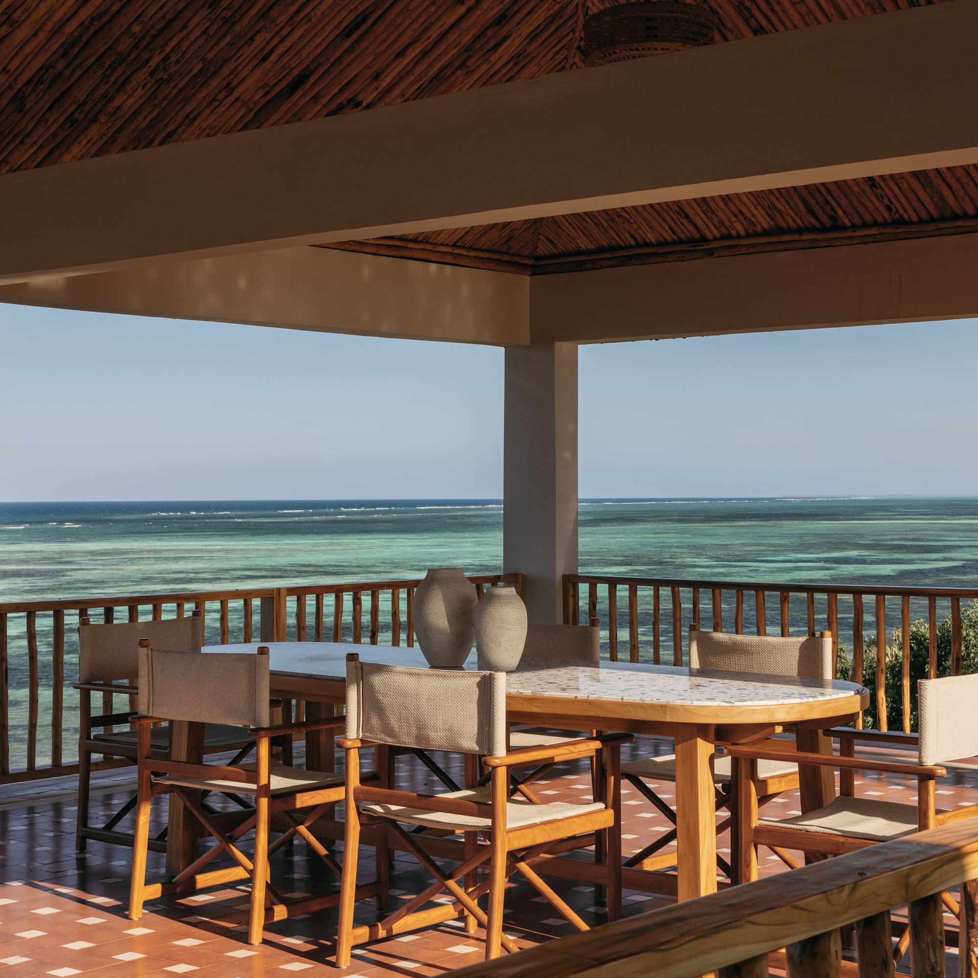 a table and chairs on a deck overlooking the ocean