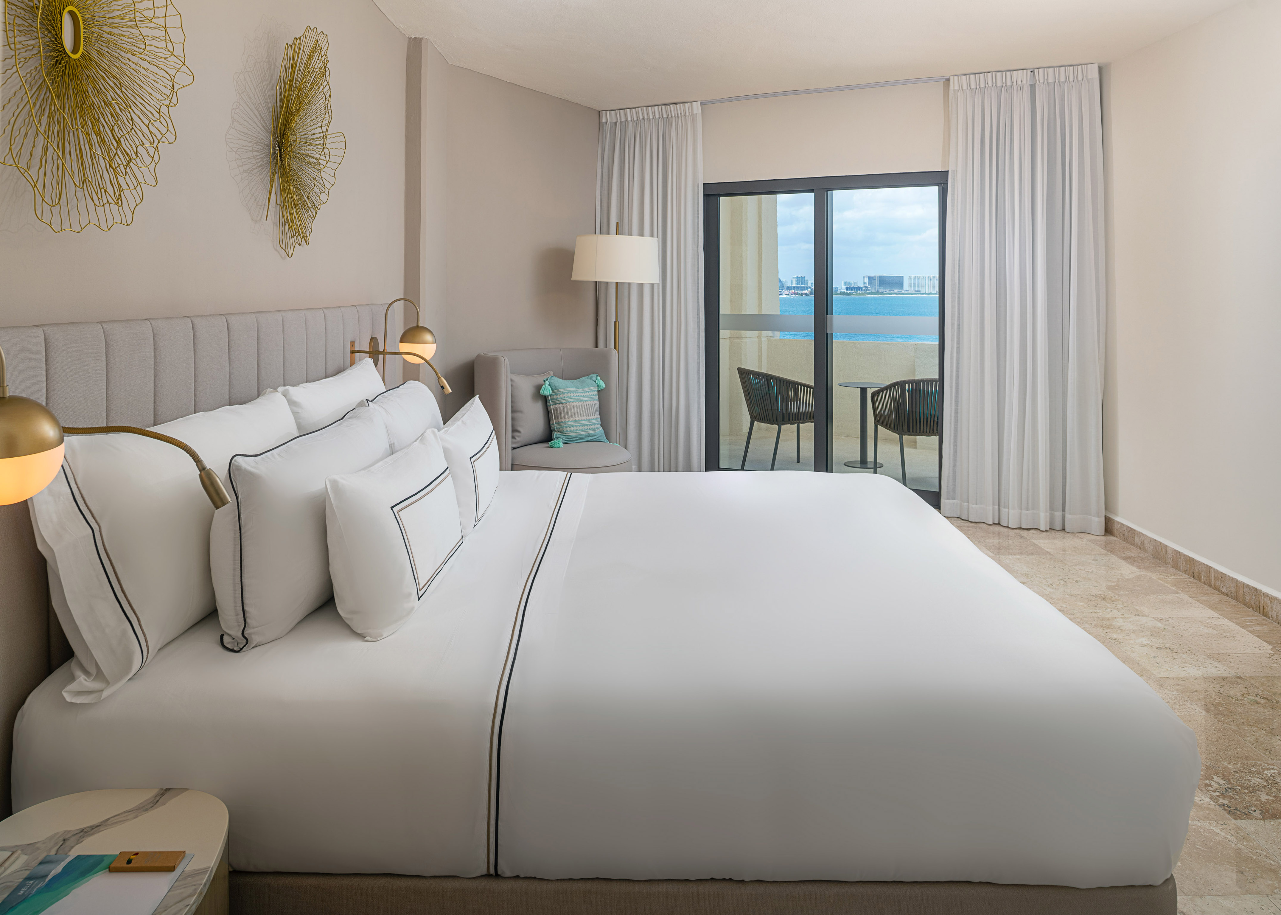 Luxury hotel bedroom with ocean view balcony, king bed, and modern decor.