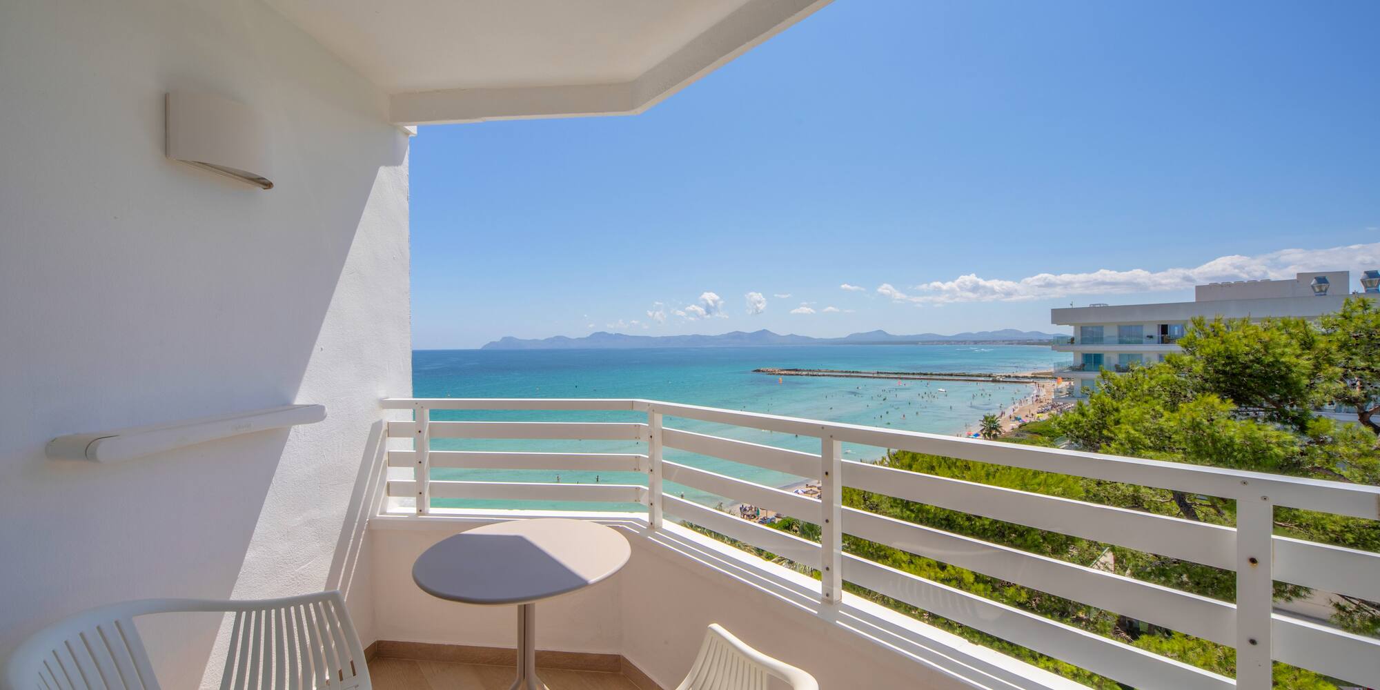 a balcony with chairs and a table overlooking the ocean