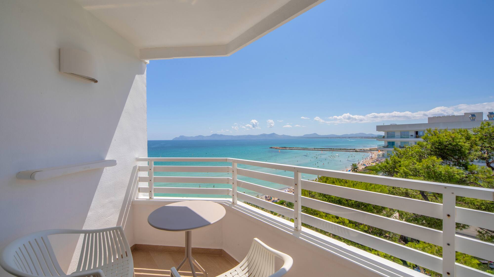 a balcony with chairs and a table overlooking the ocean