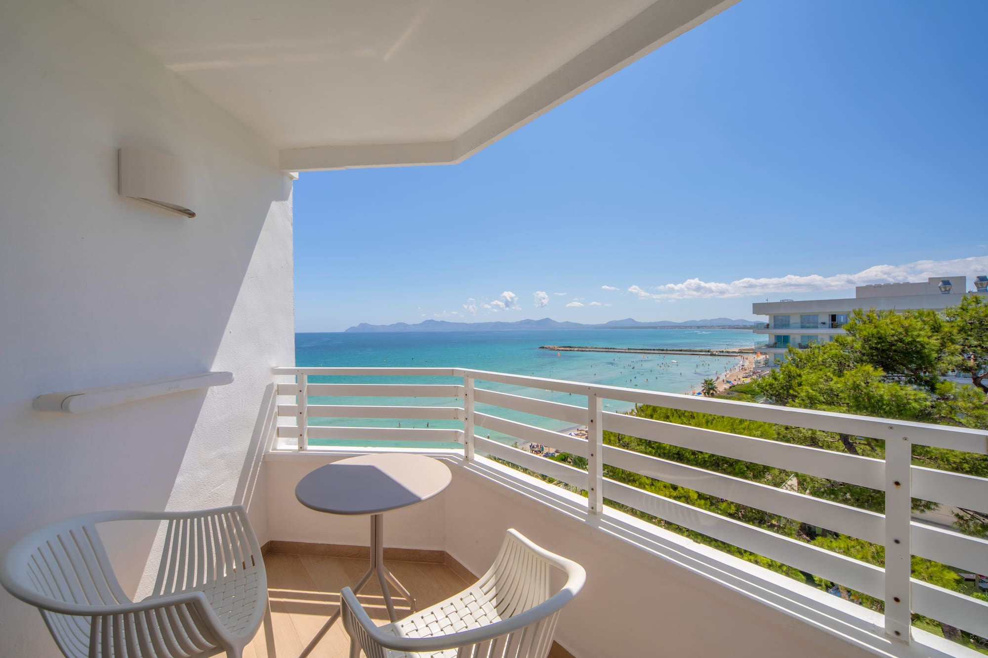 a balcony with chairs and a table overlooking the ocean