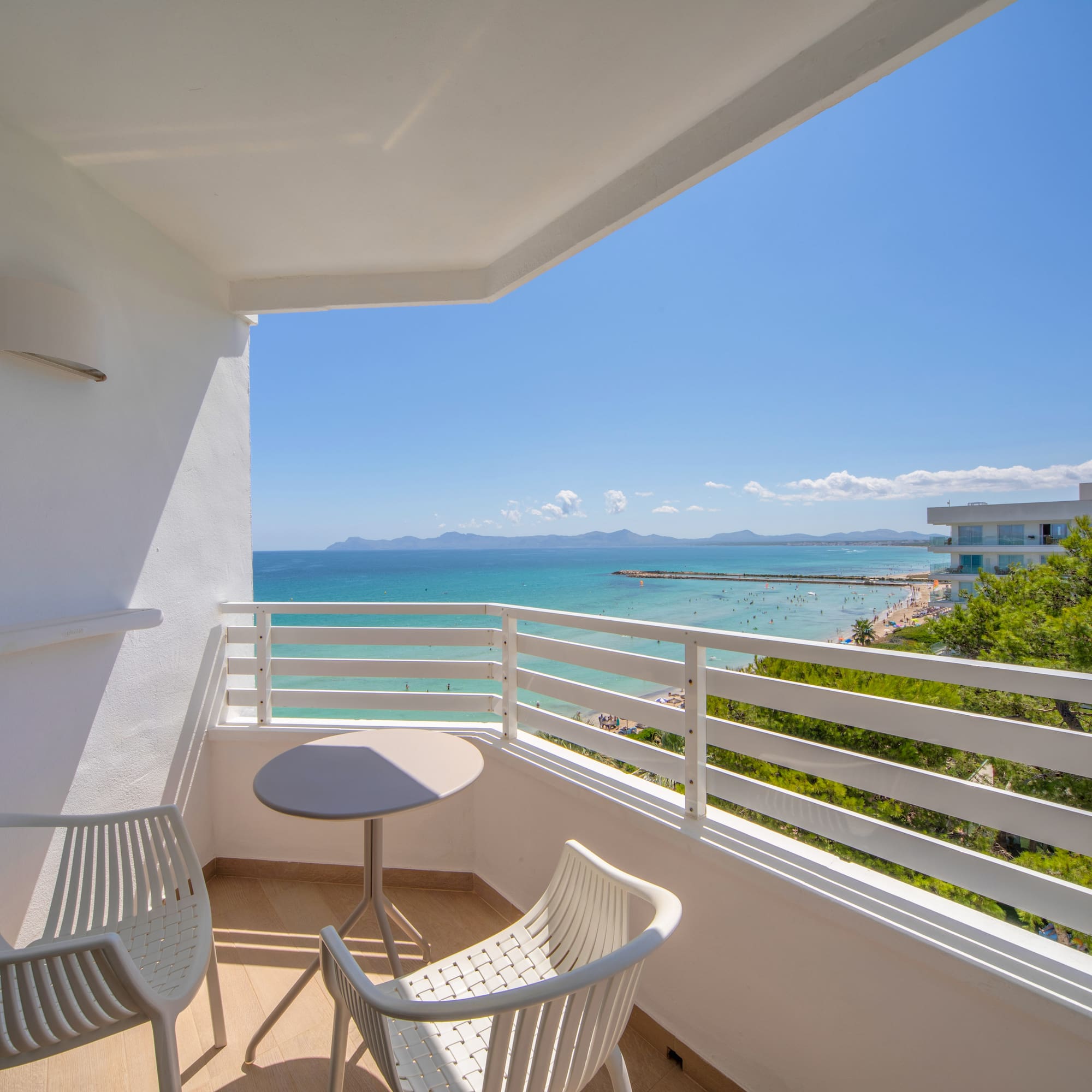 a balcony with chairs and a table overlooking the ocean