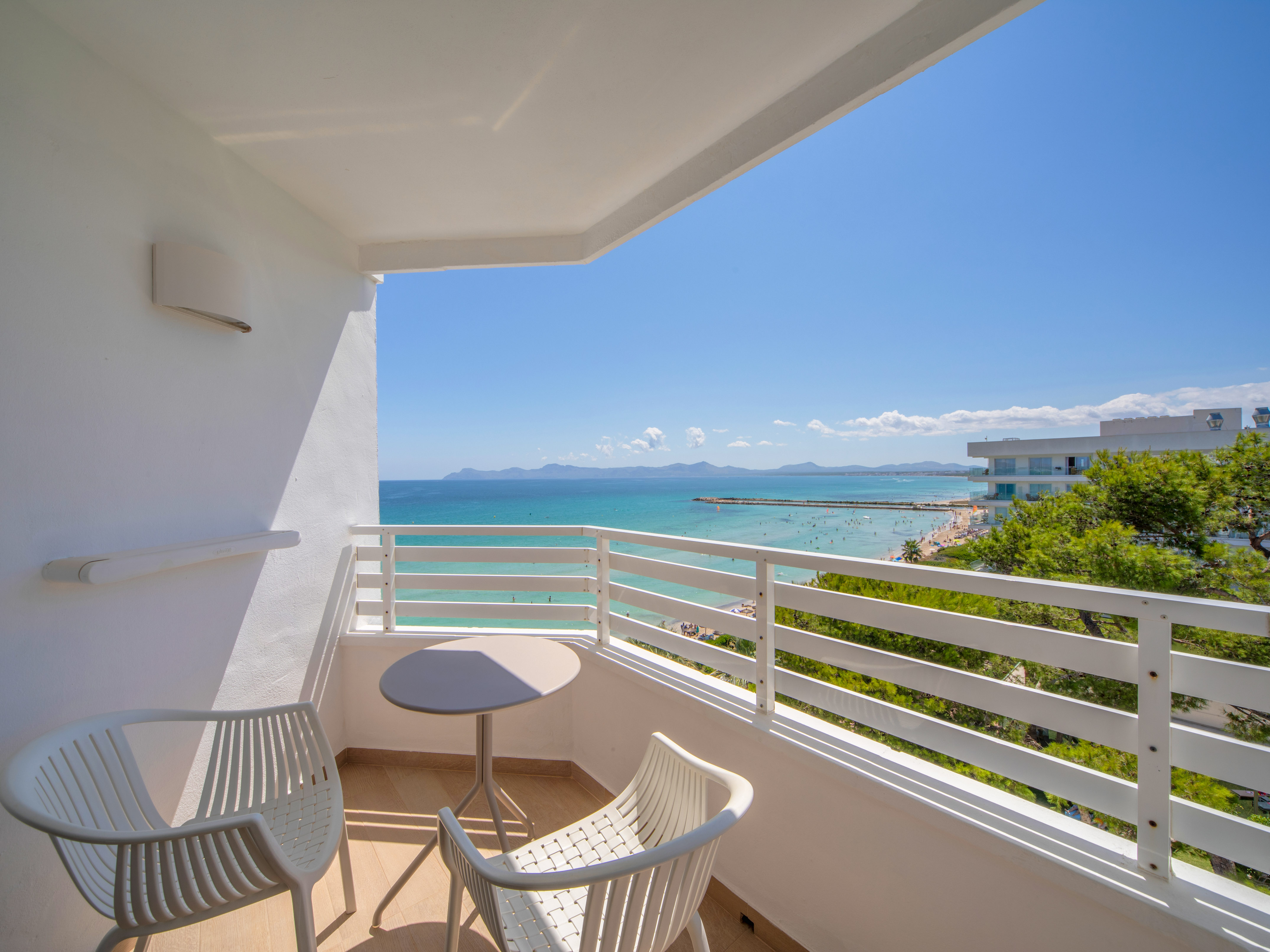 a balcony with chairs and a table overlooking the ocean