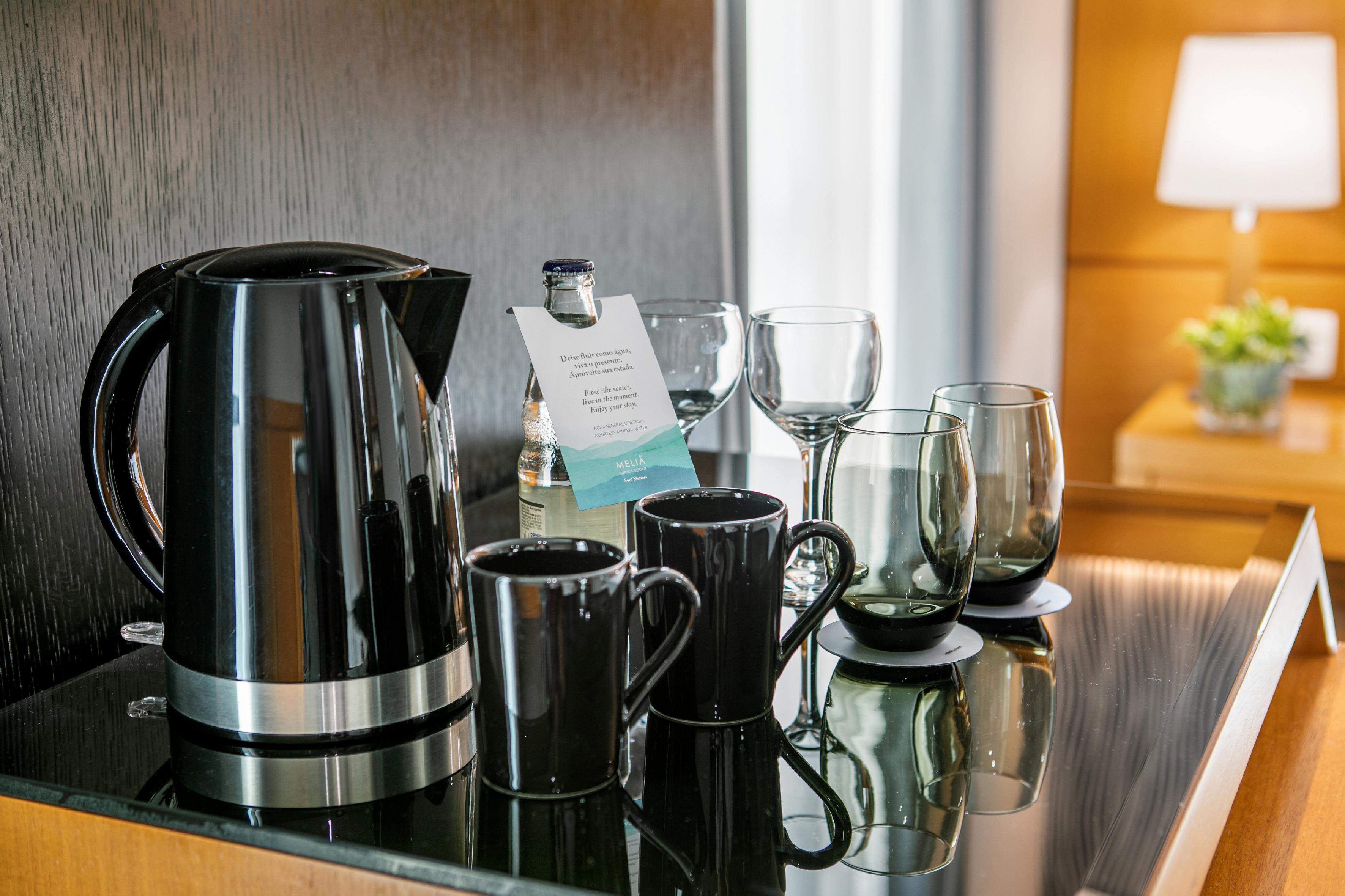 Hotel room amenities: black kettle, mugs, glasses, and complimentary water.