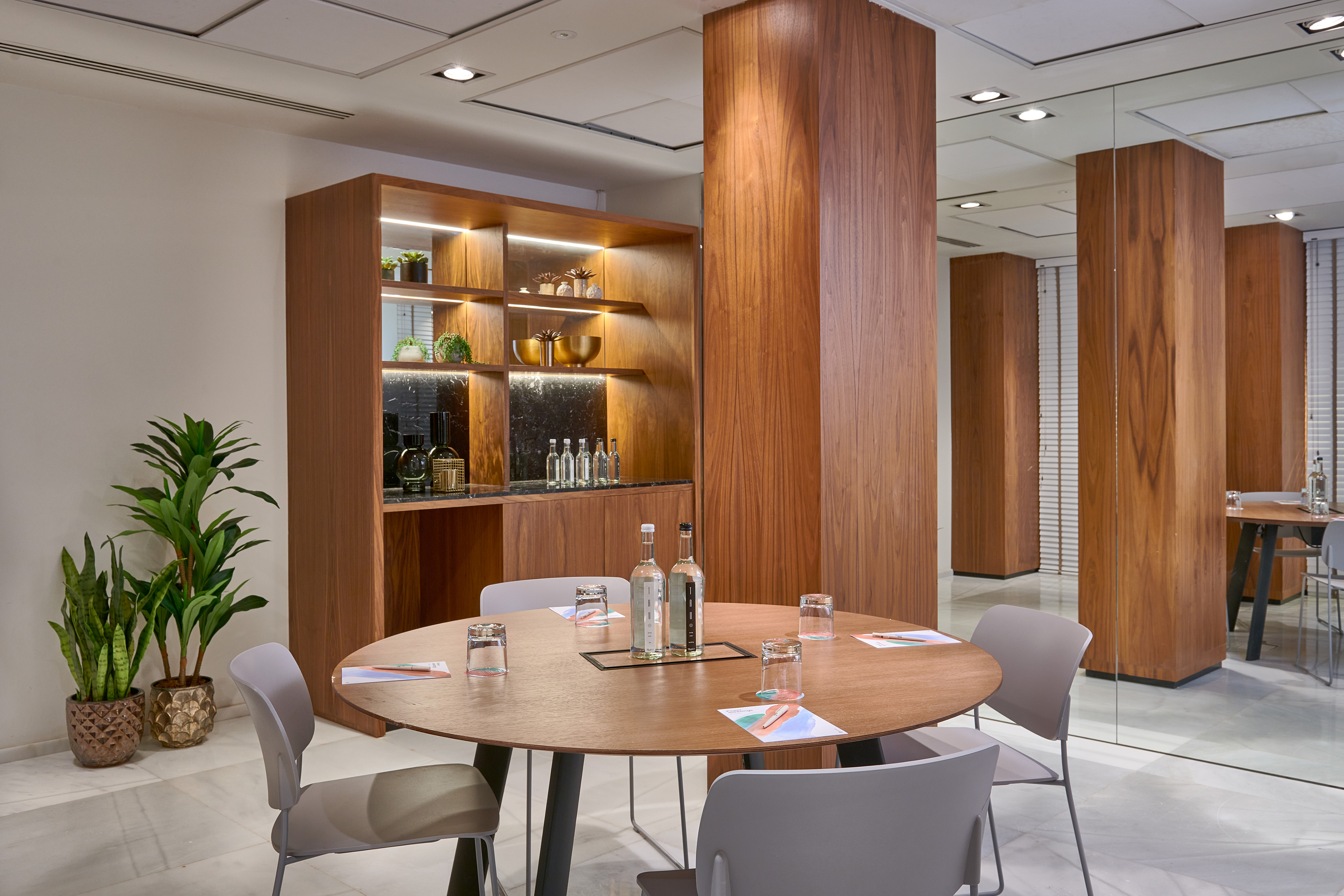 Contemporary meeting space with round wooden table, chairs, and wood decor.