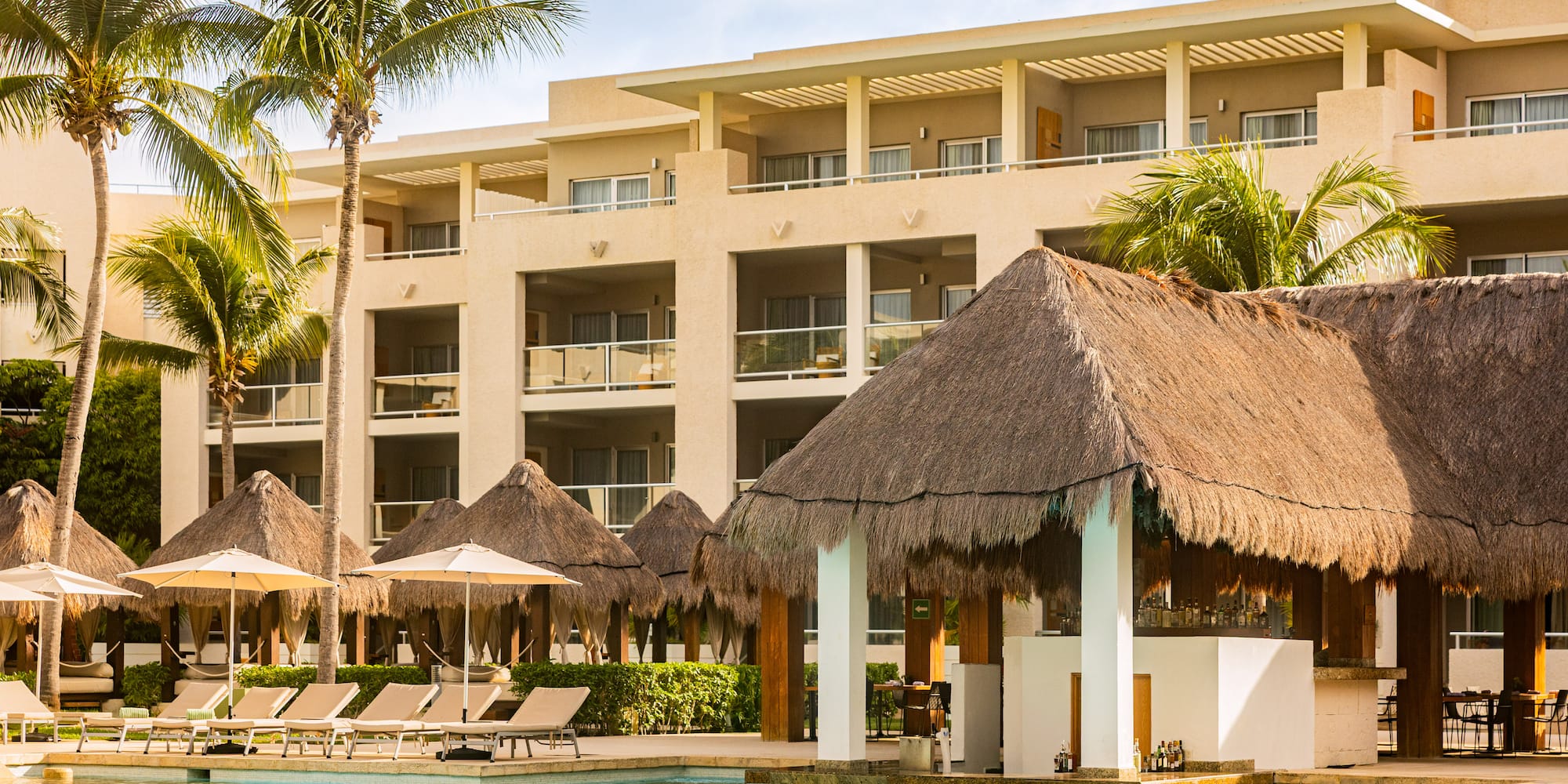 Tropical resort hotel with swimming pool, palm trees, and swim-up bar.